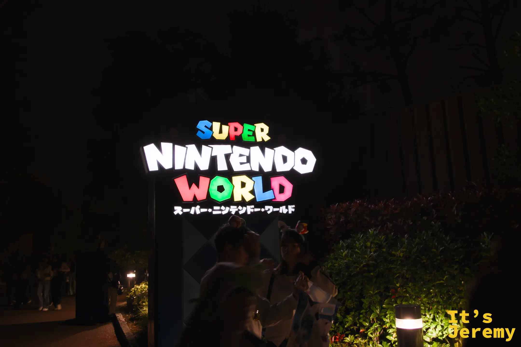 SNW 霓虹招牌特寫，「SUPER NINTENDO WORLD」的日文假名「スーパー・ニンテンドー・ワールド」在夜色中發著七彩光