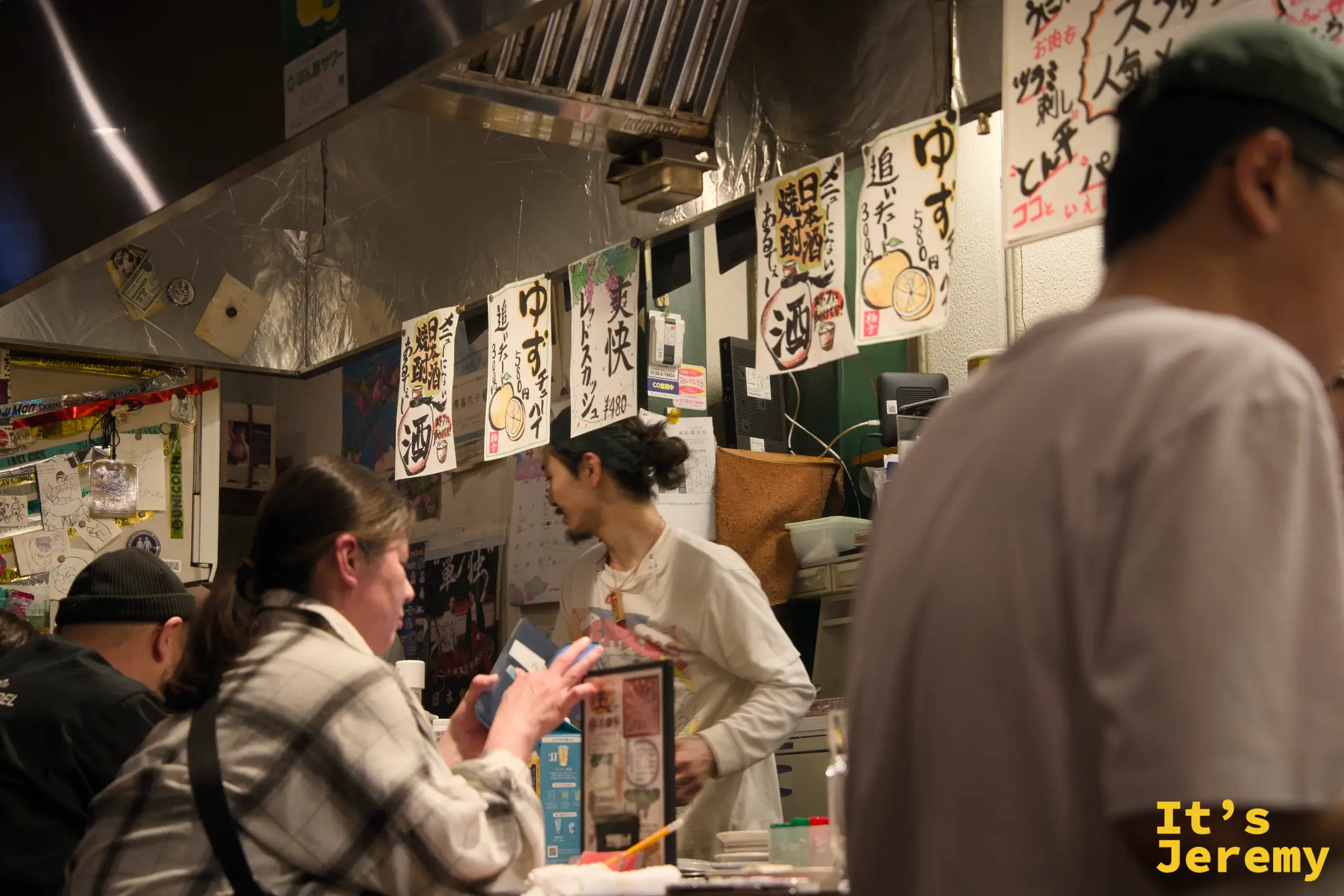 熱鬧的吧台座位區，客人與店員的距離極近，牆上掛著手寫柚子酒招牌