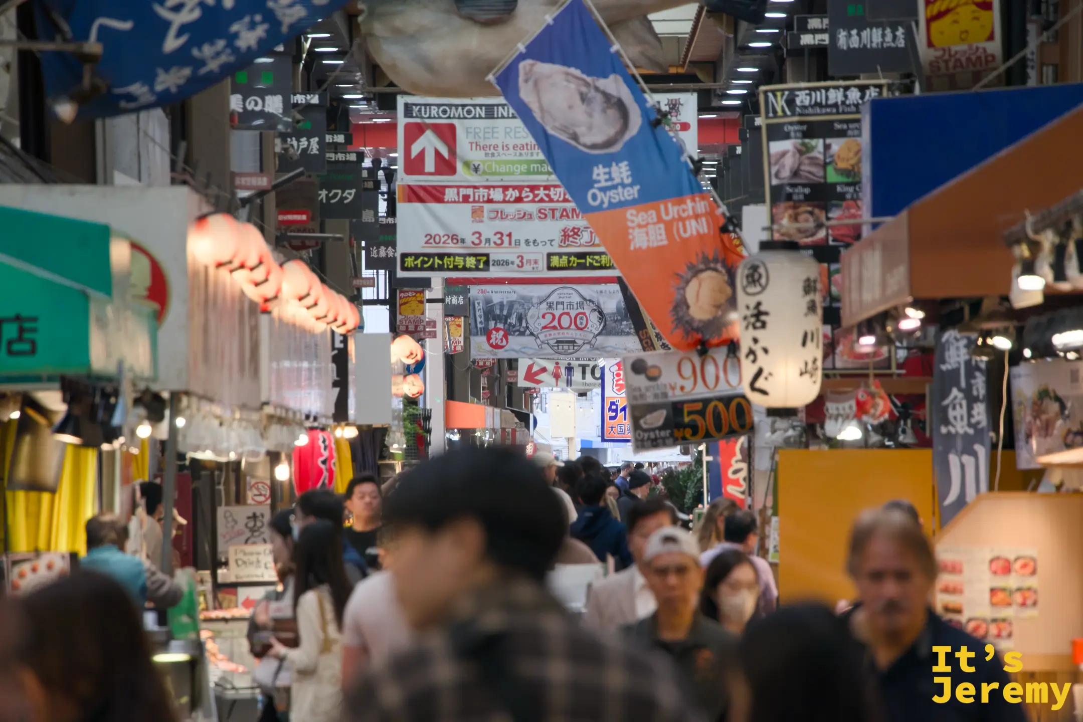 市場中段最熱鬧的地帶，牡蠣與海膽廣告旗幟高掛頭頂