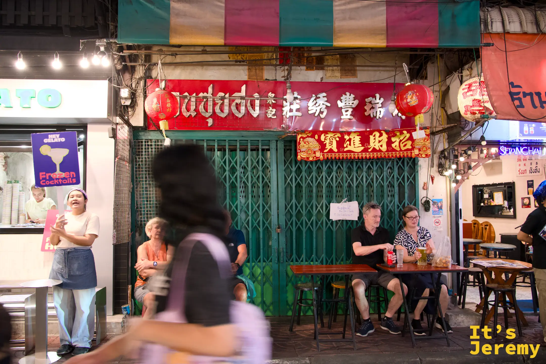 唐人街店家招牌前坐著等餐的外國觀光客