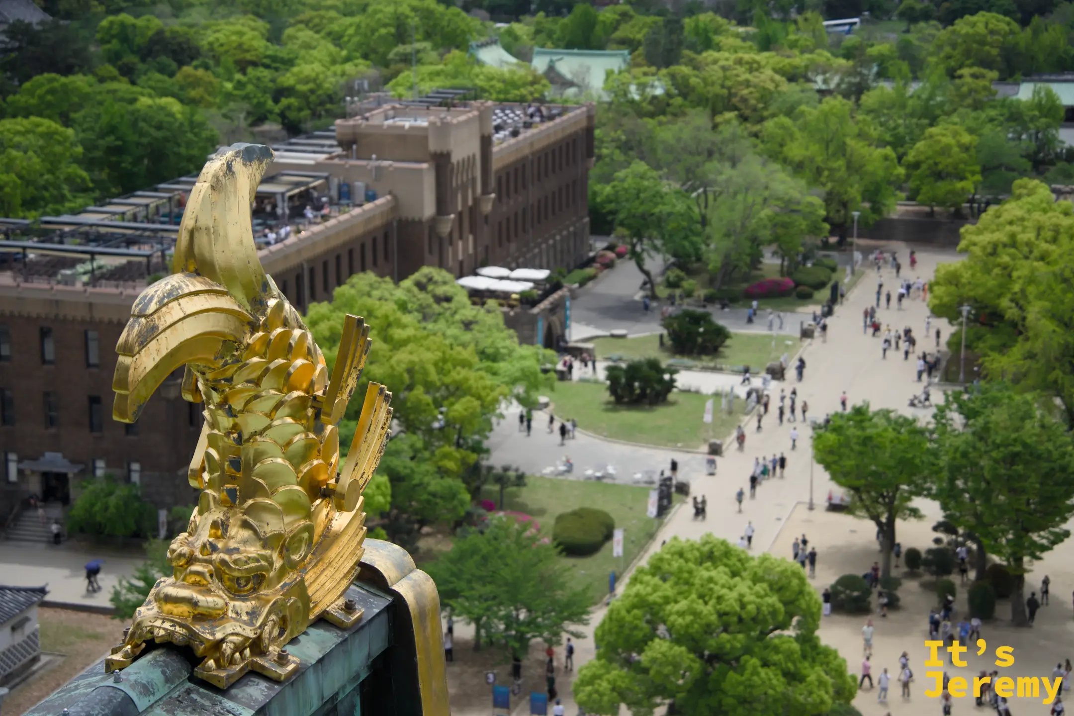 另一側金鯱特寫，遠方是大阪城公園廣場與博物館建築