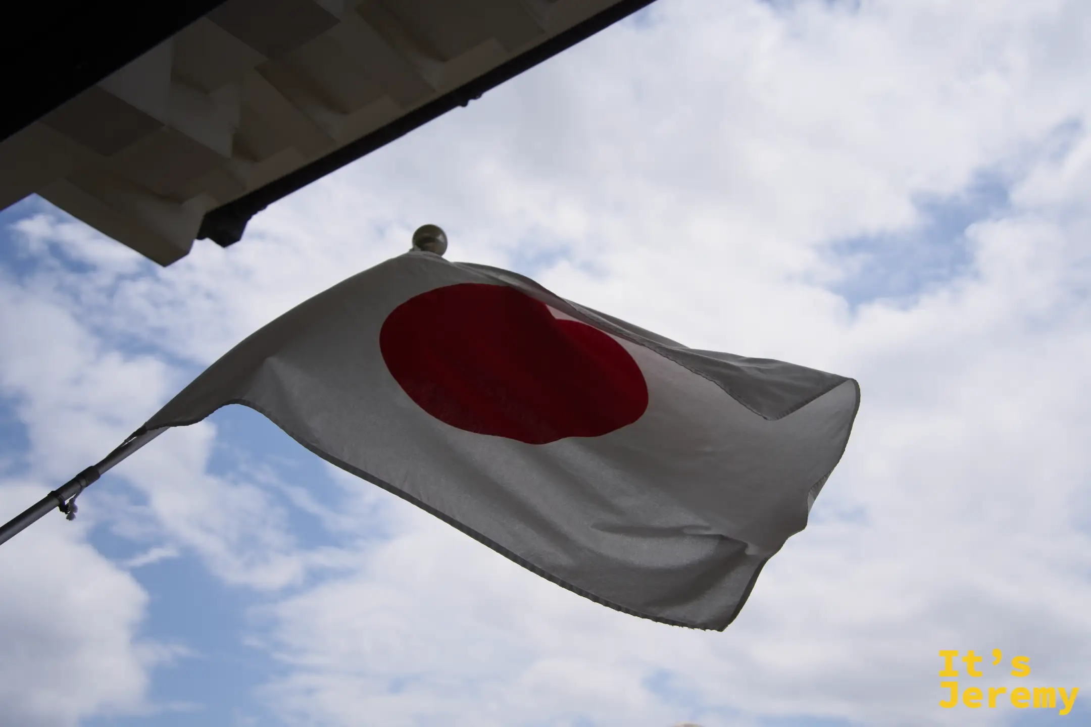 天守閣下方懸掛的日本國旗，仰角拍攝映著藍天