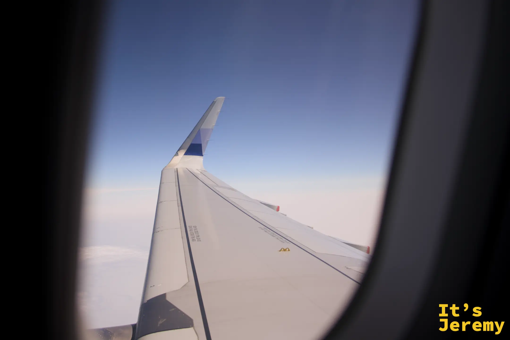 飛機窗外,機翼延伸向澄澈的藍天與白雲之間