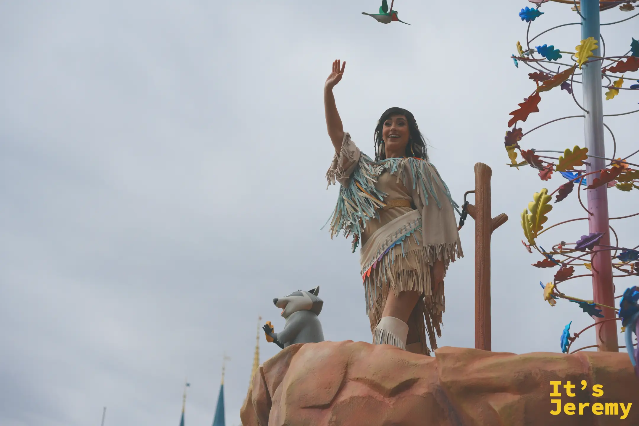 《風中奇緣》寶嘉康蒂（Pocahontas）站在花車上揮手，身旁有浣熊 Meeko