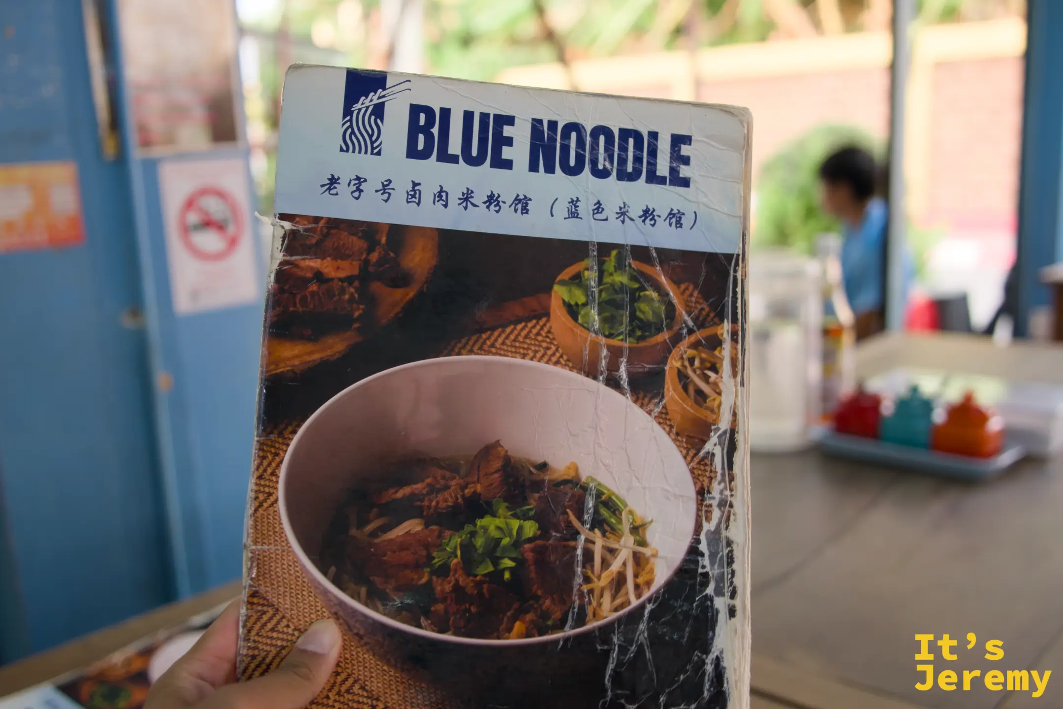 手持 Blue Noodle 菜單，封面寫著「老字號滷肉米粉館（藍色米粉館）」