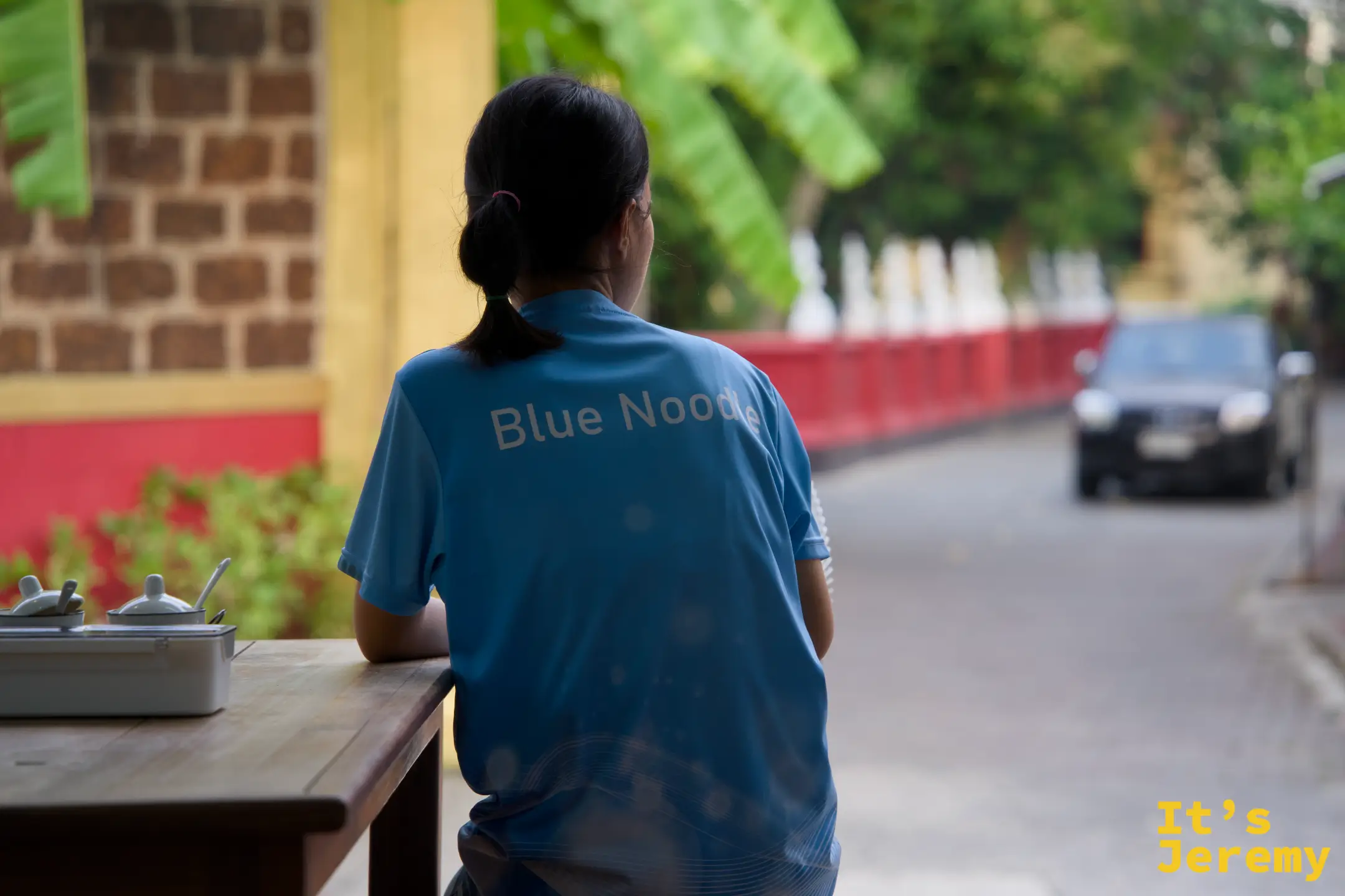 穿 Blue Noodle 制服的女店員背影，望向街道