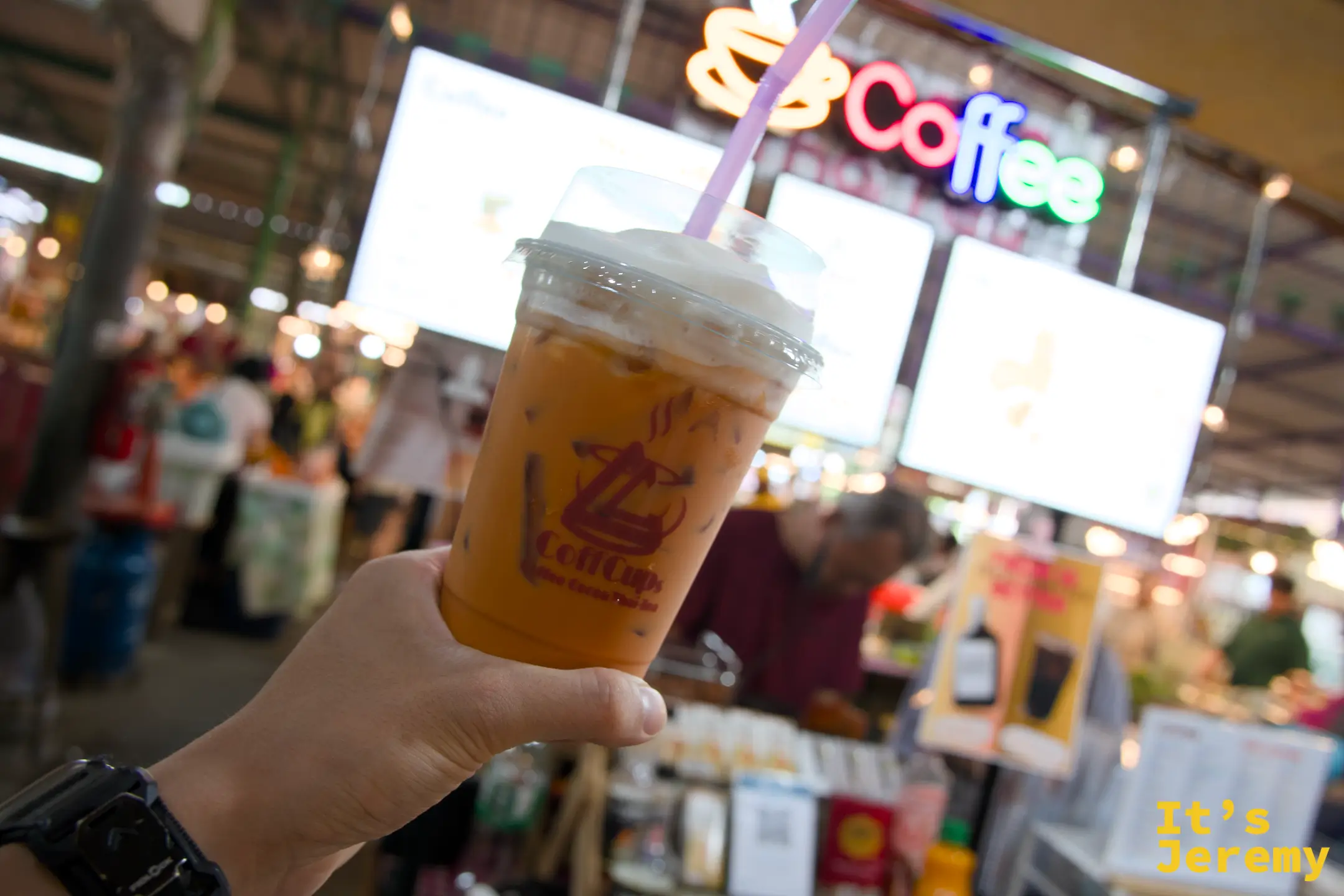 邊走邊喝的泰奶，背景的霓虹 Coffee 招牌在強光下還是亮著