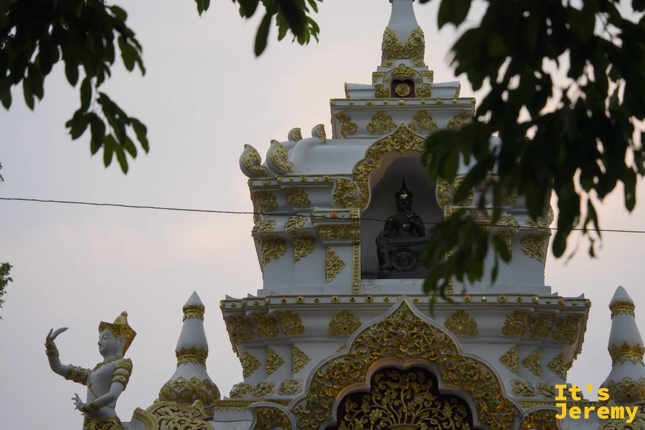 圍牆角落的白色金飾建築細節,穿透樹梢依稀可見