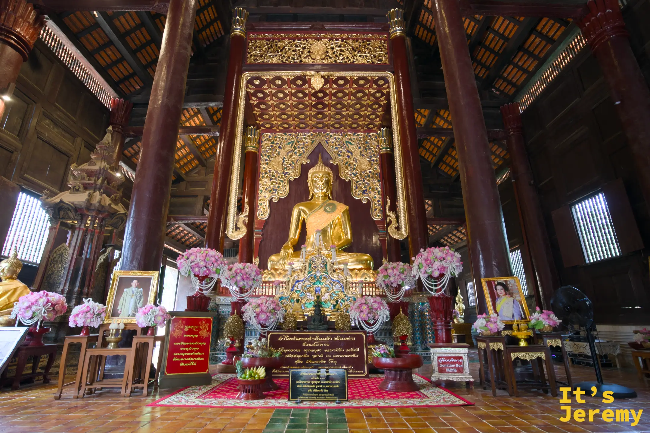 盼道寺大殿全景，金身主佛坐在木造高台上，兩側掛著泰國國王相框
