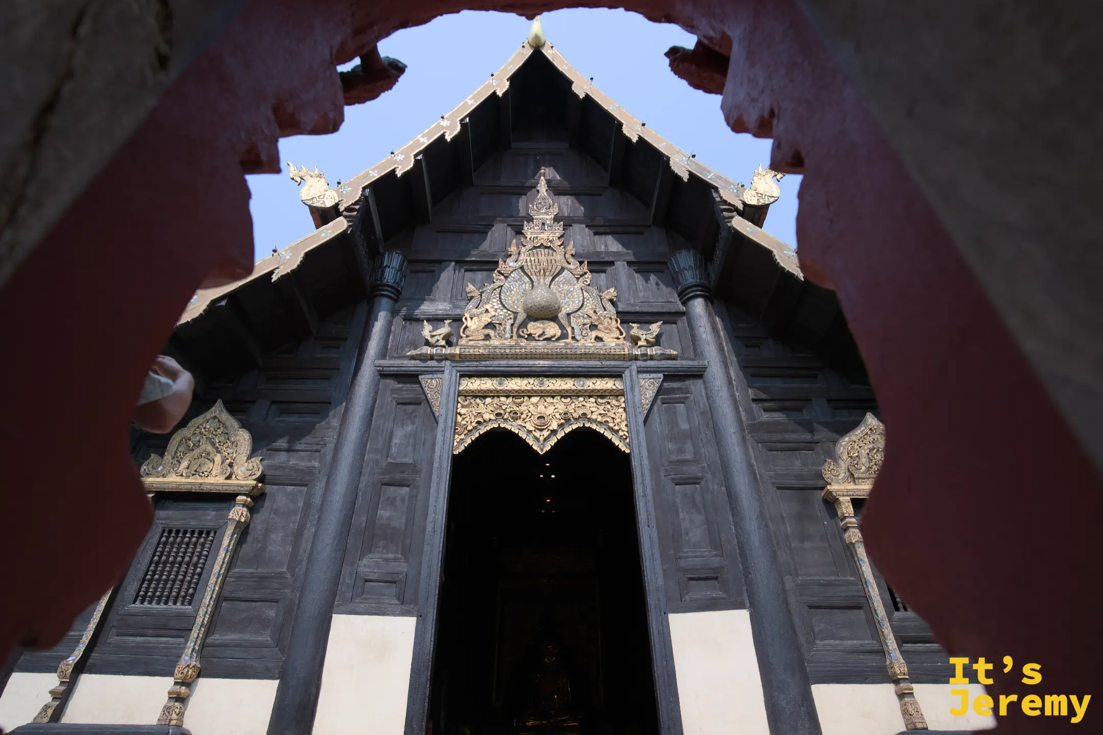 從朱紅院牆缺口望入盼道寺，百年柚木大殿被院牆自然框住