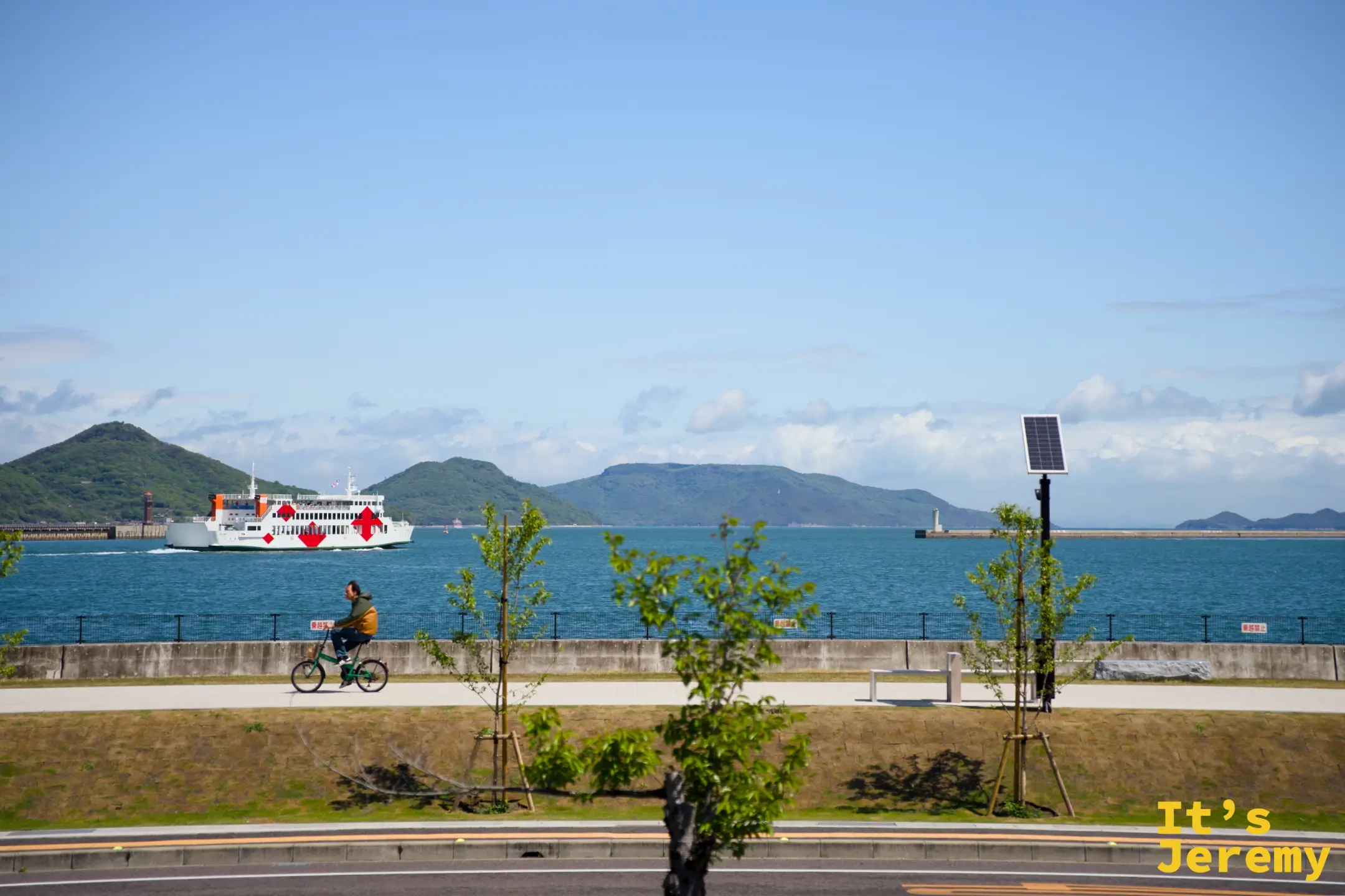 海岸道路邊，一艘開往直島的渡輪划過翠藍的瀨戶內海