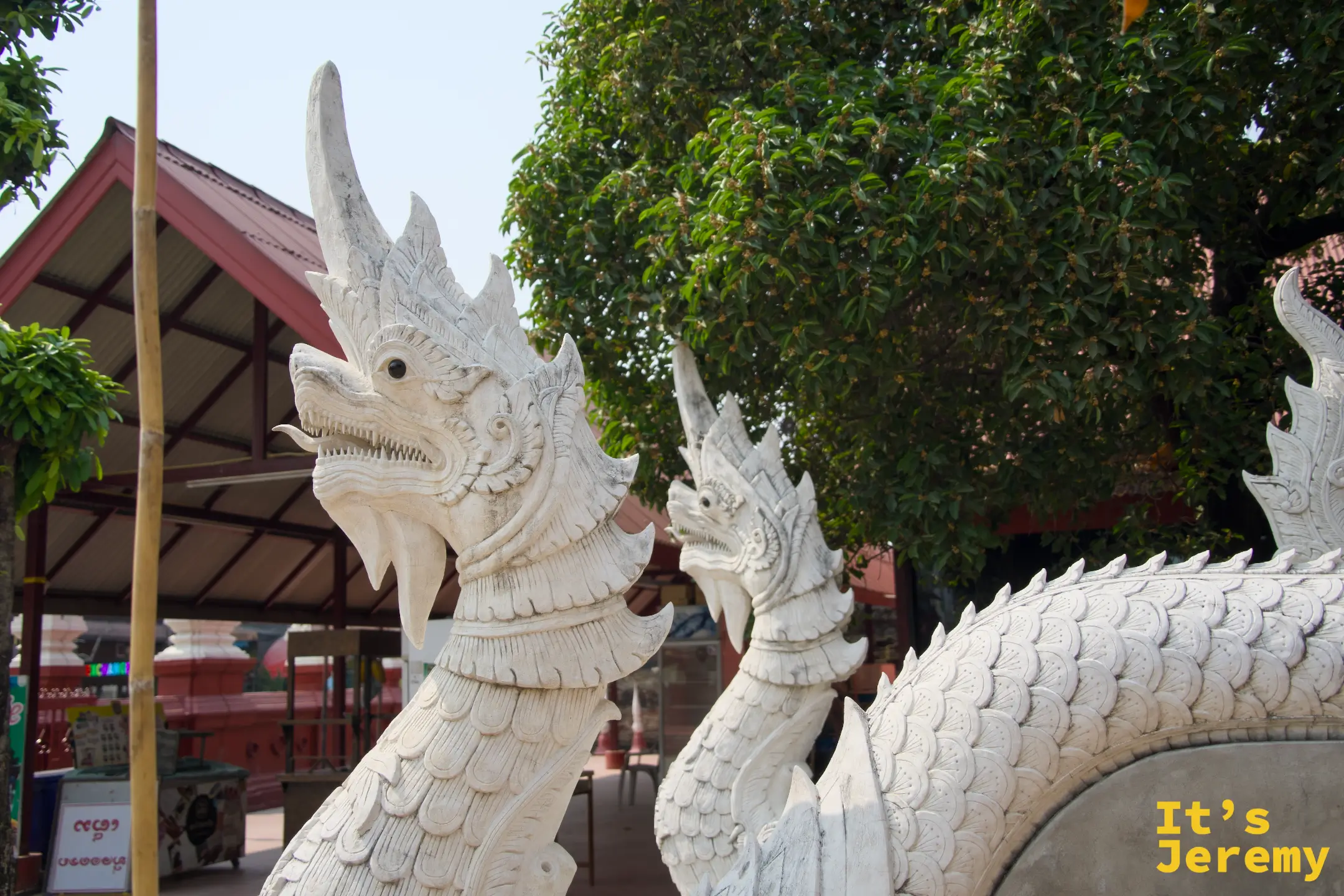 兩頭白色那伽蛇神守護像，昂頭張口，樹木為背景