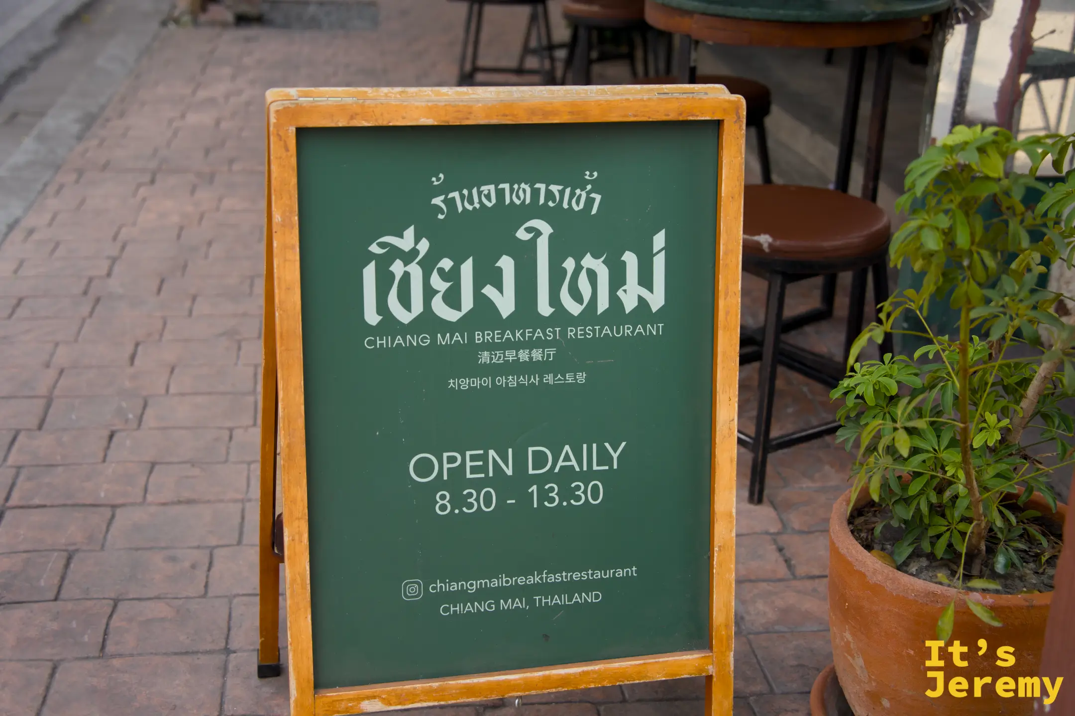 店外深綠色 A-frame 立牌，寫著 OPEN DAILY 8:30-13:30 與 IG 帳號