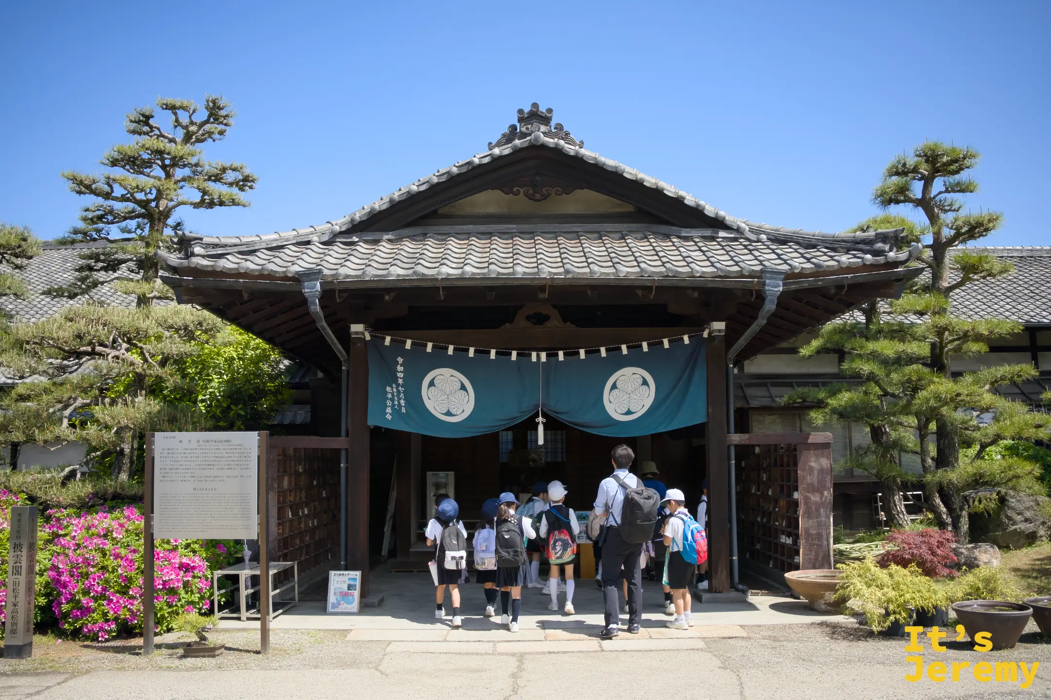 小學外教生魚貫走進披雲閣大門，藍色幕布與松平家紋在視覺上很有儀式感