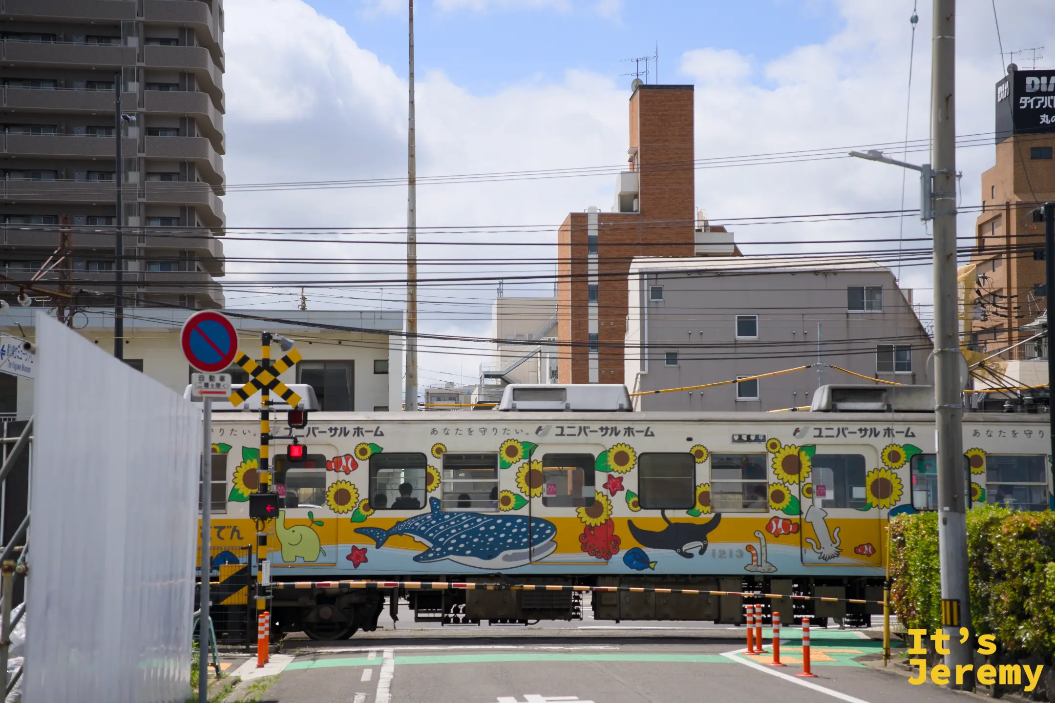 平交道等候時，一列車身布滿向日葵與鯨鯊等海洋生物彩繪圖案的琴電列車緩緩通過