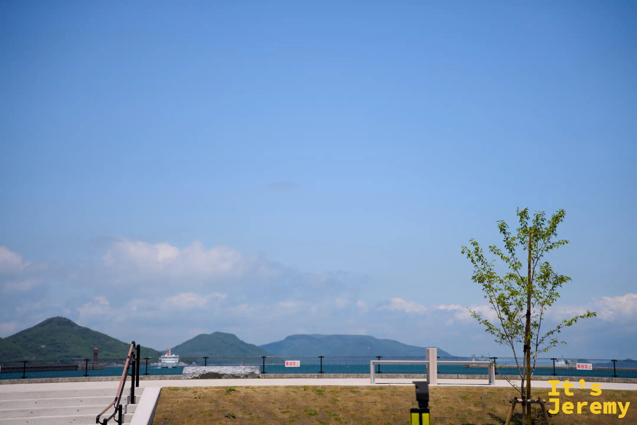 北濱一帶望向港口方向，藍天下開闊的瀬戶內海海面延伸至對岸，渡輪與丘陵剪影清晰可見