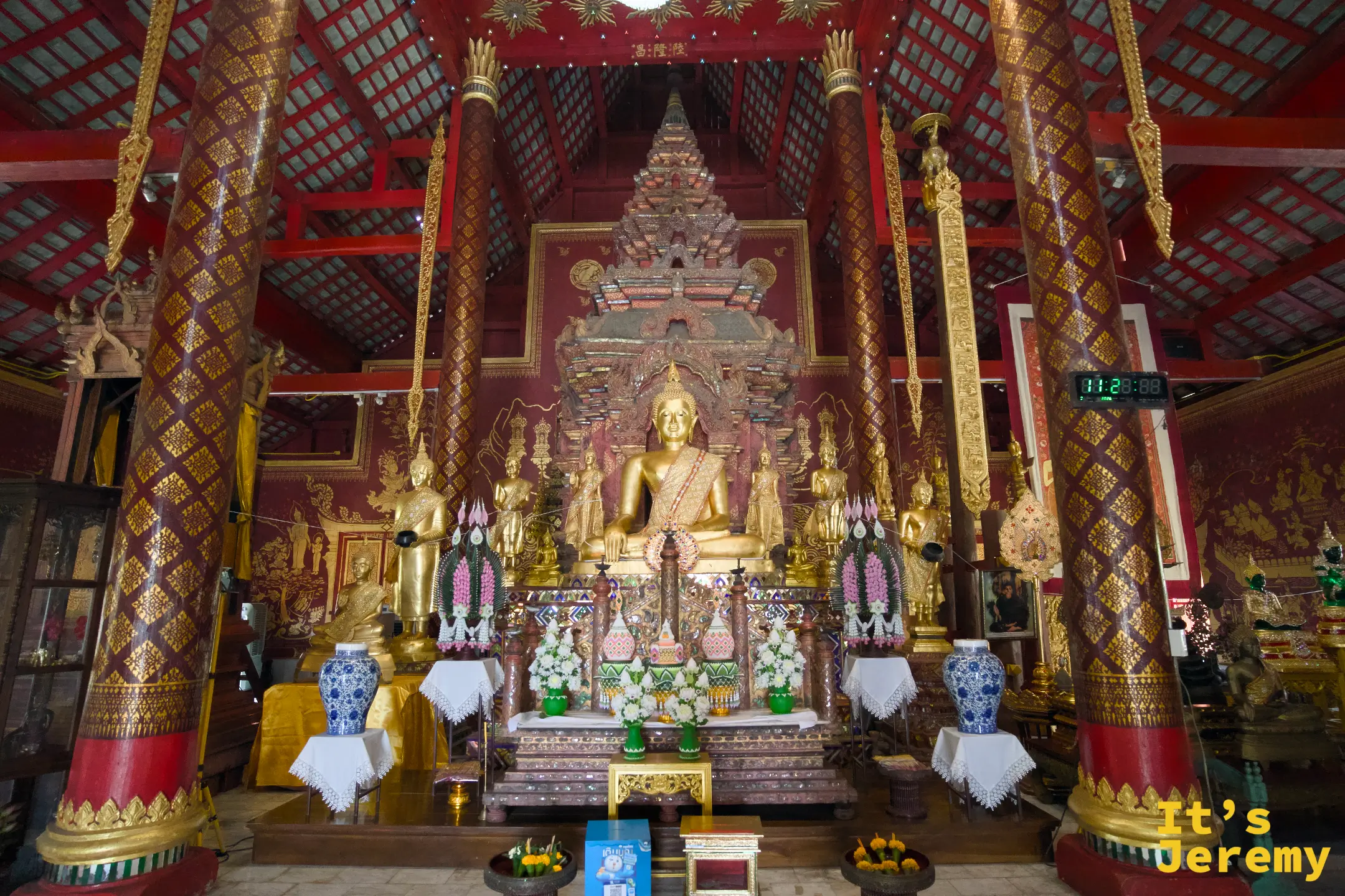 主殿主佛龕，金佛端坐，周圍佛像與花環陳列精緻