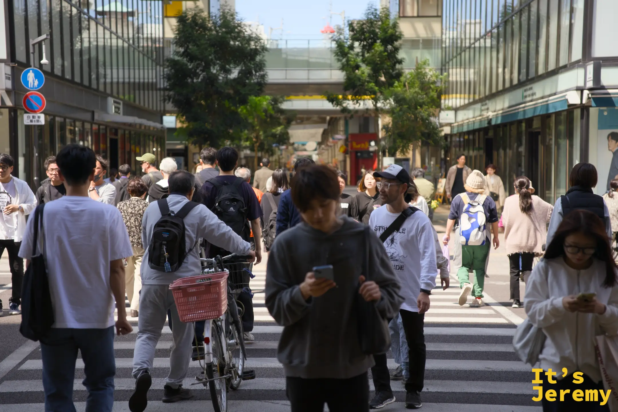 丸亀町商店街入口附近的十字路口，行人與騎自行車的市民各走各路，熱鬧而有秩序