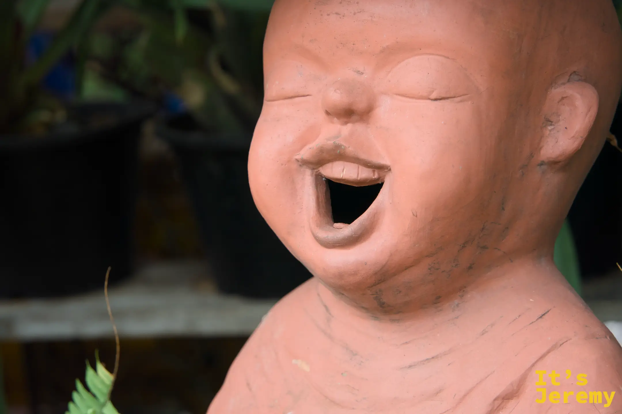 陶土笑臉僧侶像特寫，五官細節清晰，大笑的表情充滿感染力