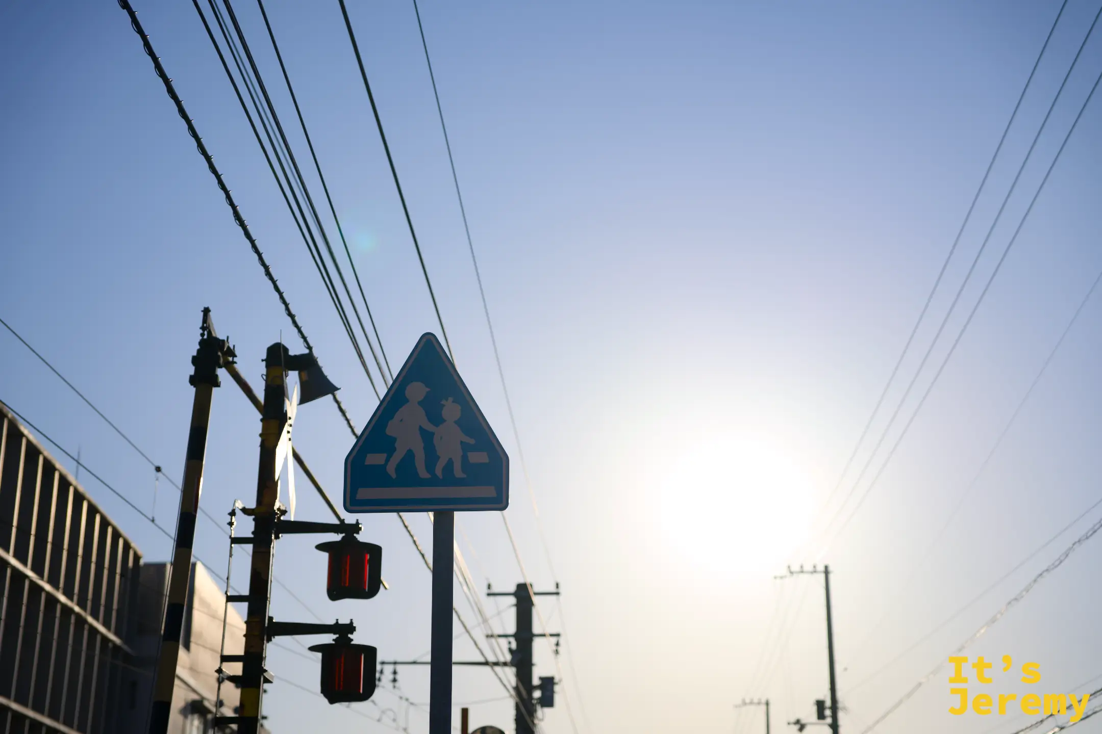 車站周邊街道，電線橫空，藍色兒童路標和紅燈組成一個典型的日本小鎮路口