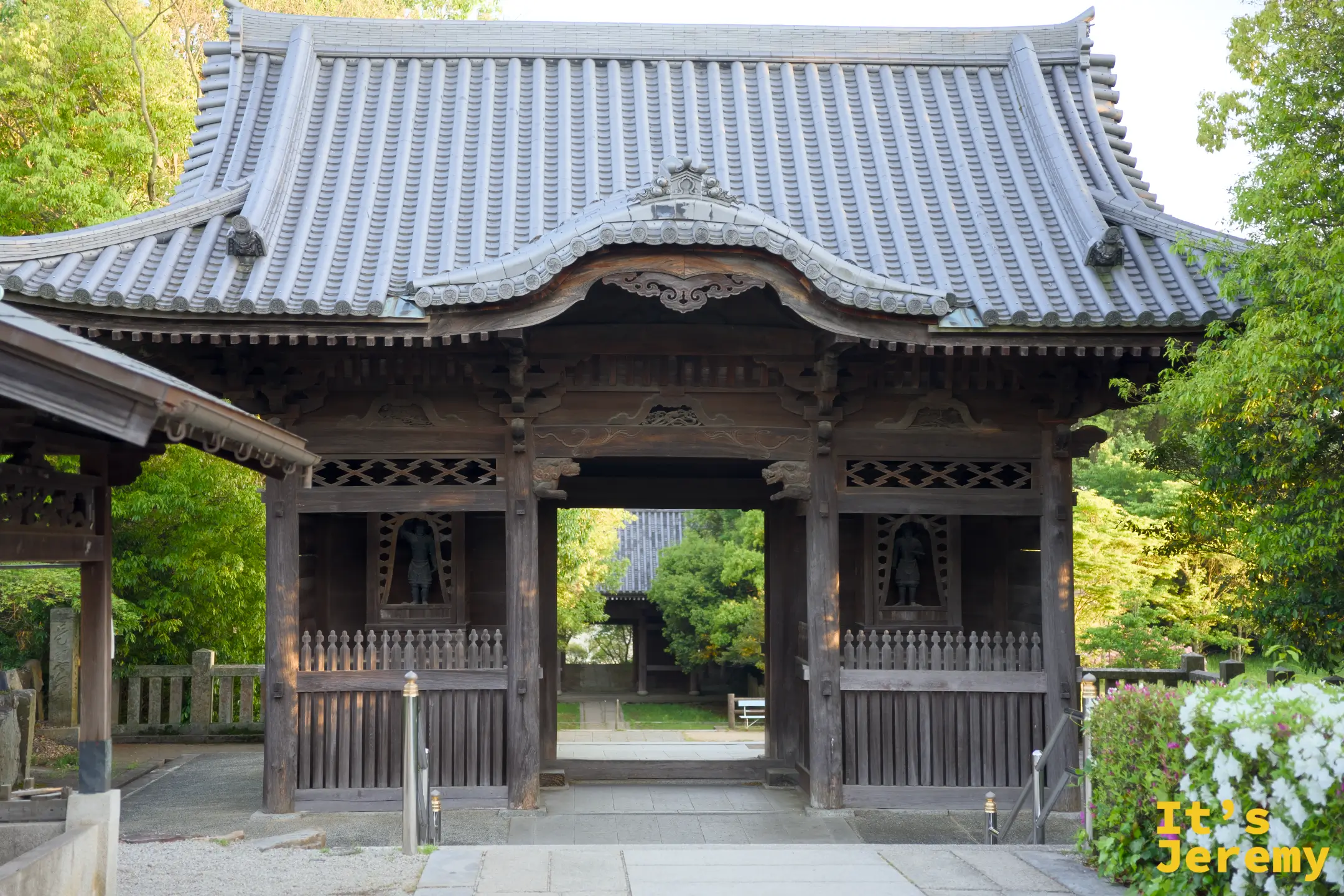 屋島寺山門（仁王門）外觀，木造建築兩側白花盛開，灰瓦屋頂簡樸厚重