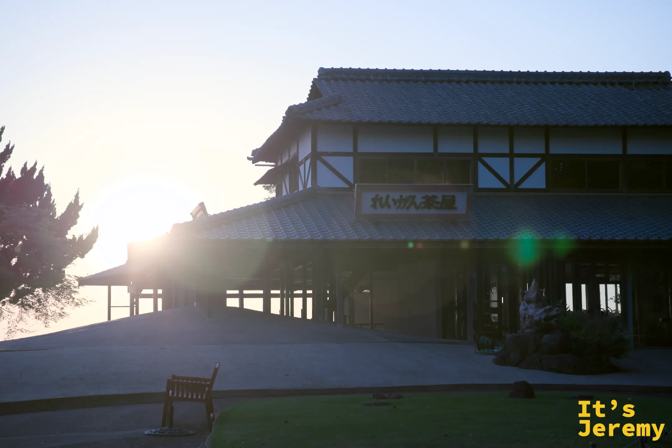 靈巖茶屋逆光黃昏，「れいがん茶屋」招牌在強烈光暈中，太陽從建築左側正面穿透