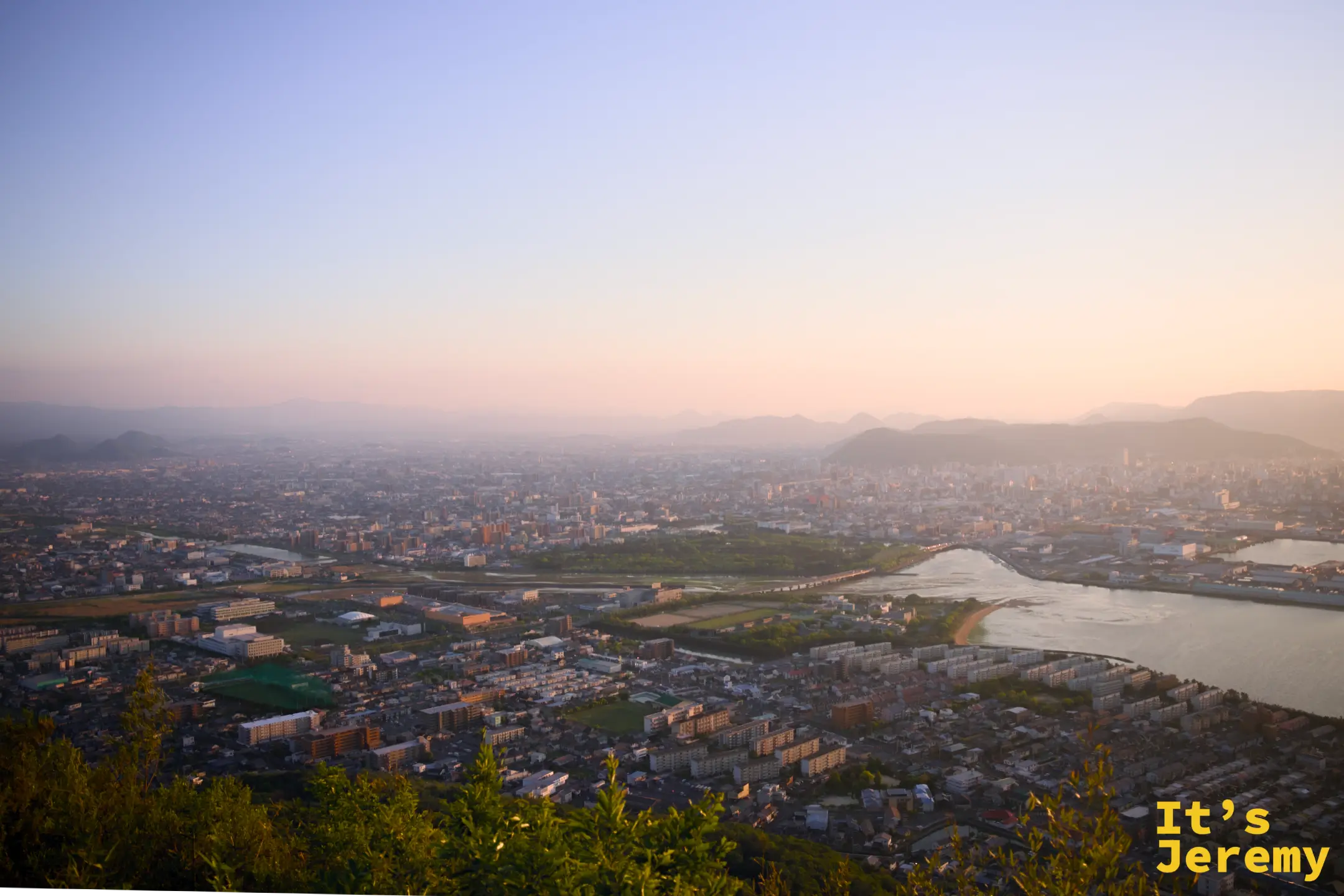 日落後轉向市區側，高松市區和蓬萊川在藍紫色天空下，城市燈光正在醒來