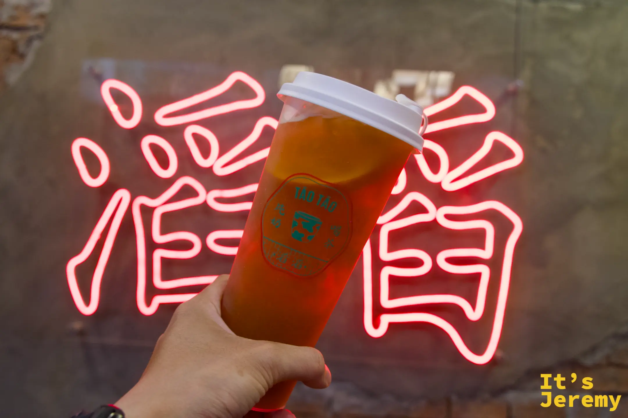 荔枝冰茶與背景的滔滔燈牌合影，店內復古色調與冰茶剛好成對比