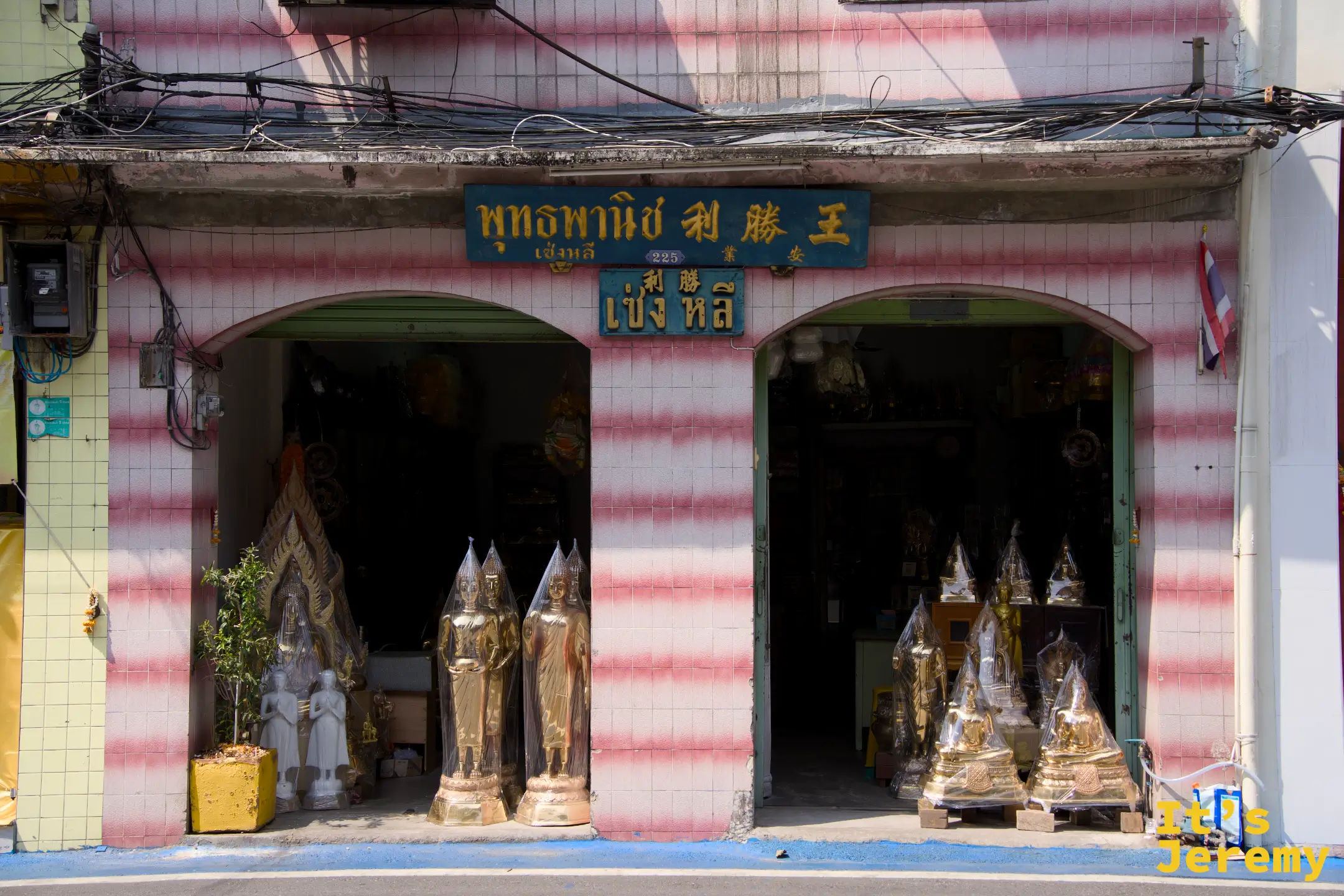粉紅白條紋外牆的佛具店「พุทธพาณิช 利勝王」，這條街上隨處可見的中泰雙語招牌