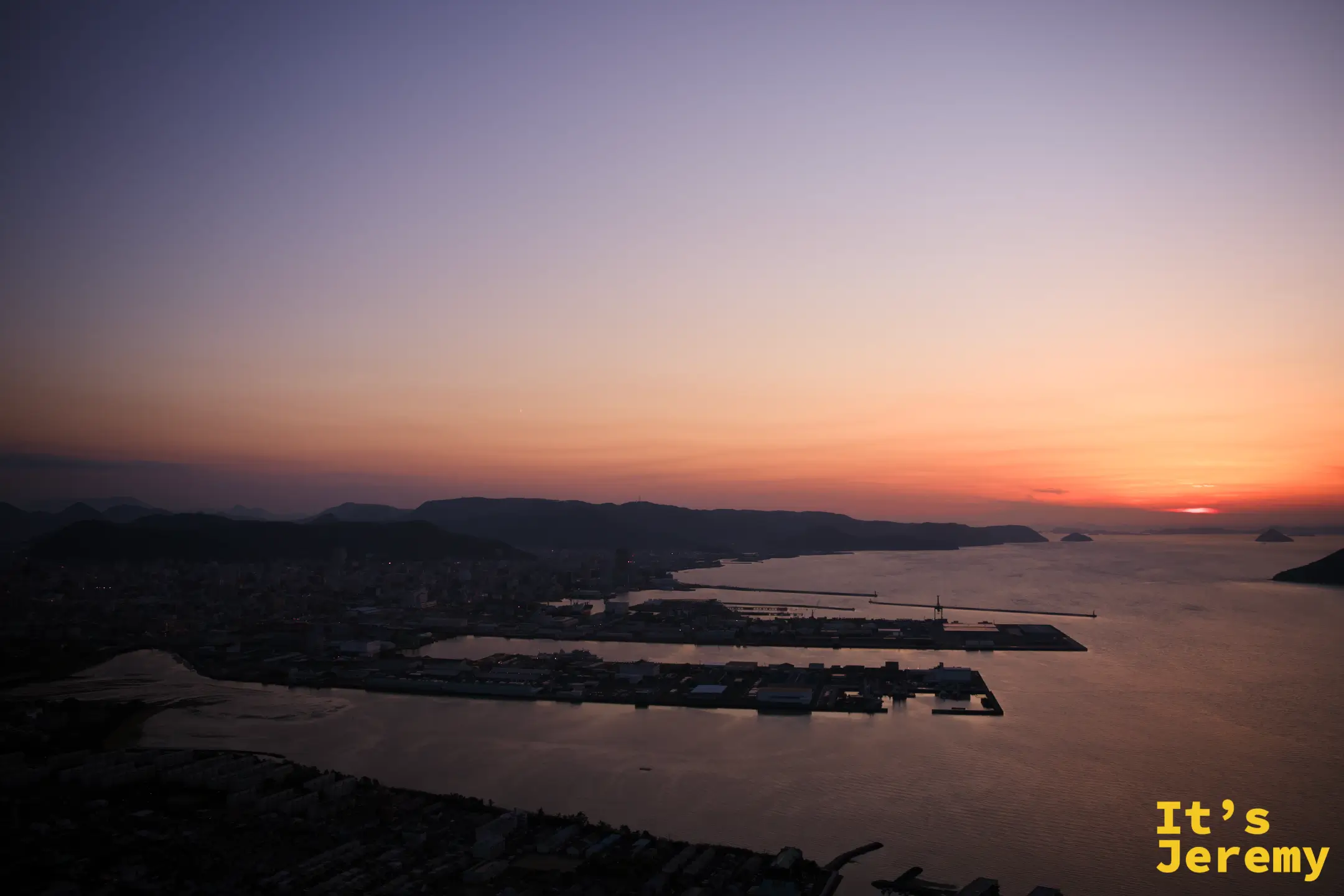 日落後天色轉粉橙，瀨戶內海島群剪影在清晰的光線下再次浮現，兩艘貨輪穿越海面