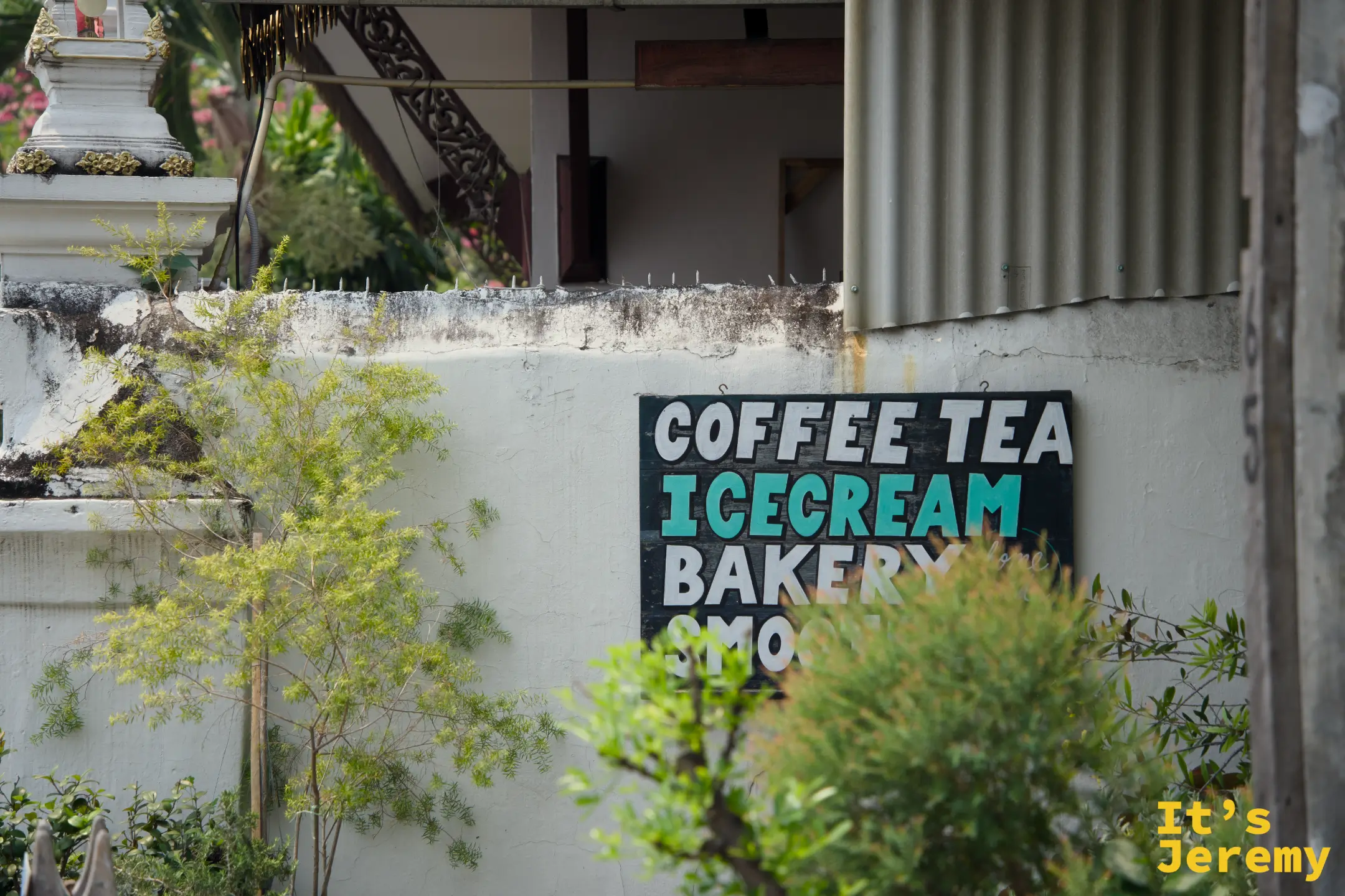 帕辛寺附近廟牆上的手繪招牌，寫著 Coffee、Tea、Ice Cream 和 Bakery，白色佛塔就在旁邊