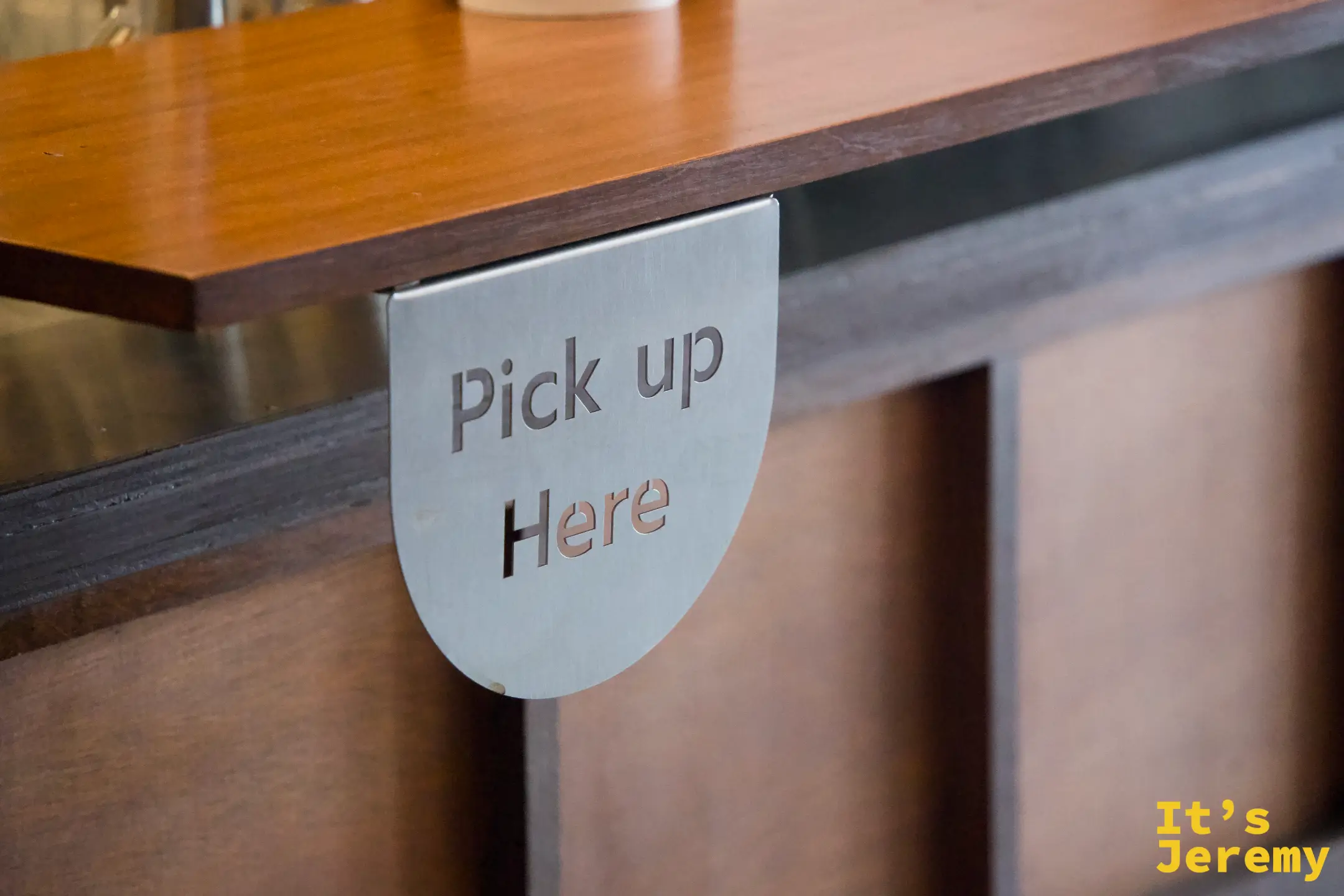 GAAD 吧台取餐區金屬標牌「Pick up Here」，細節設計一致
