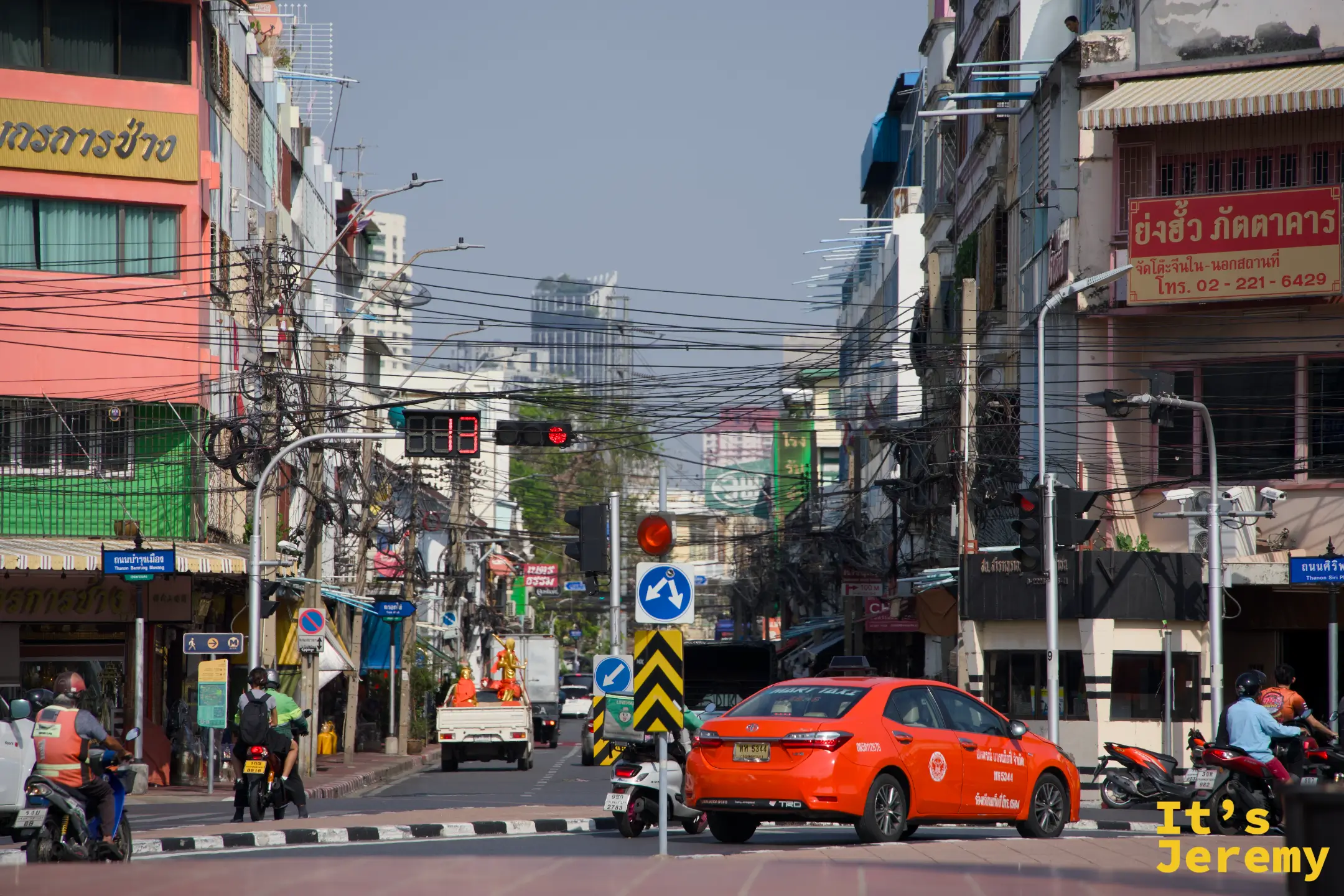 老城區街口的橘色計程車與糾結電線，傍晚的曼谷正在熱起來