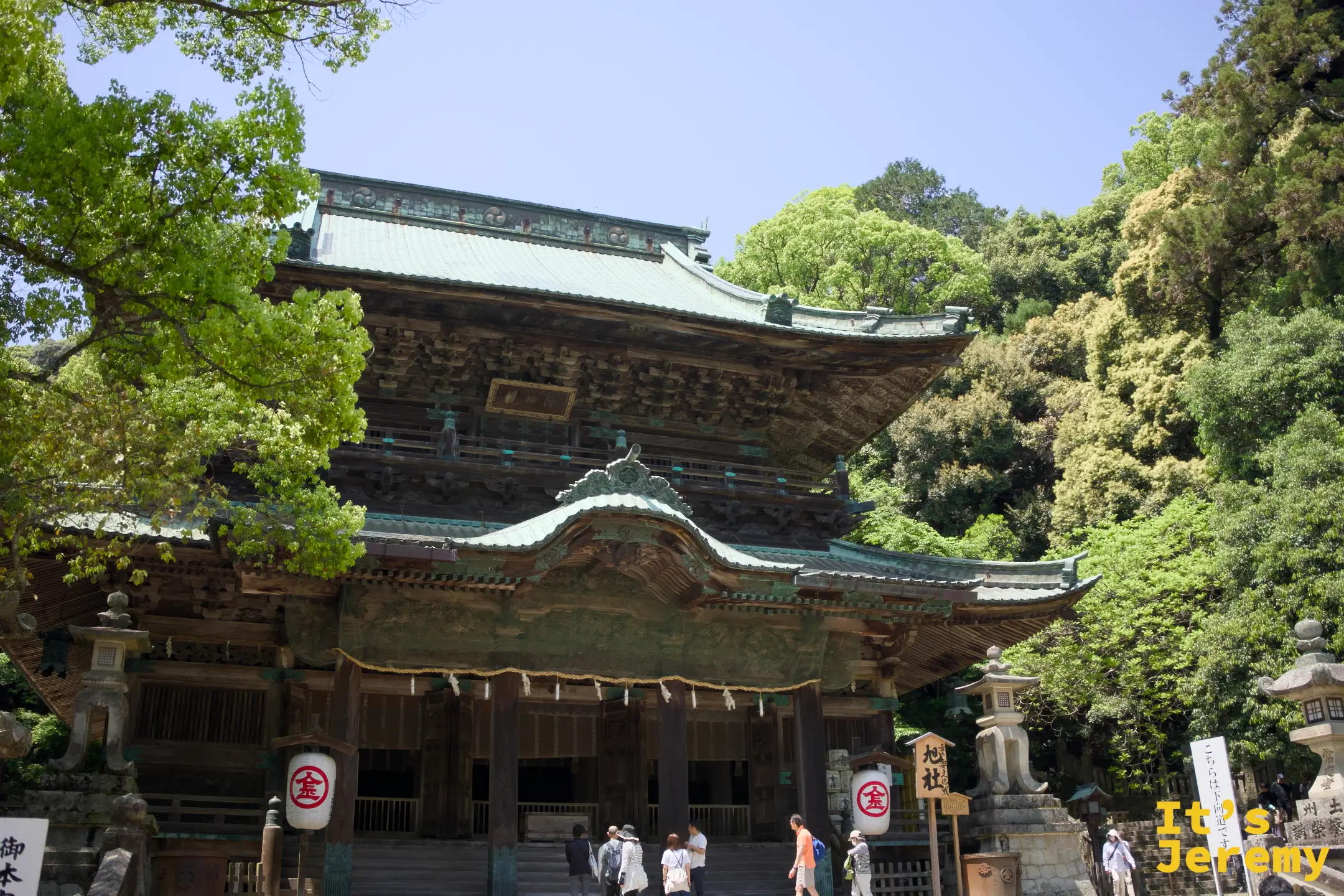 旭社正面全景，雙層飛檐的木造建築，前方石燈籠排列，右側有御本宮方向指示牌