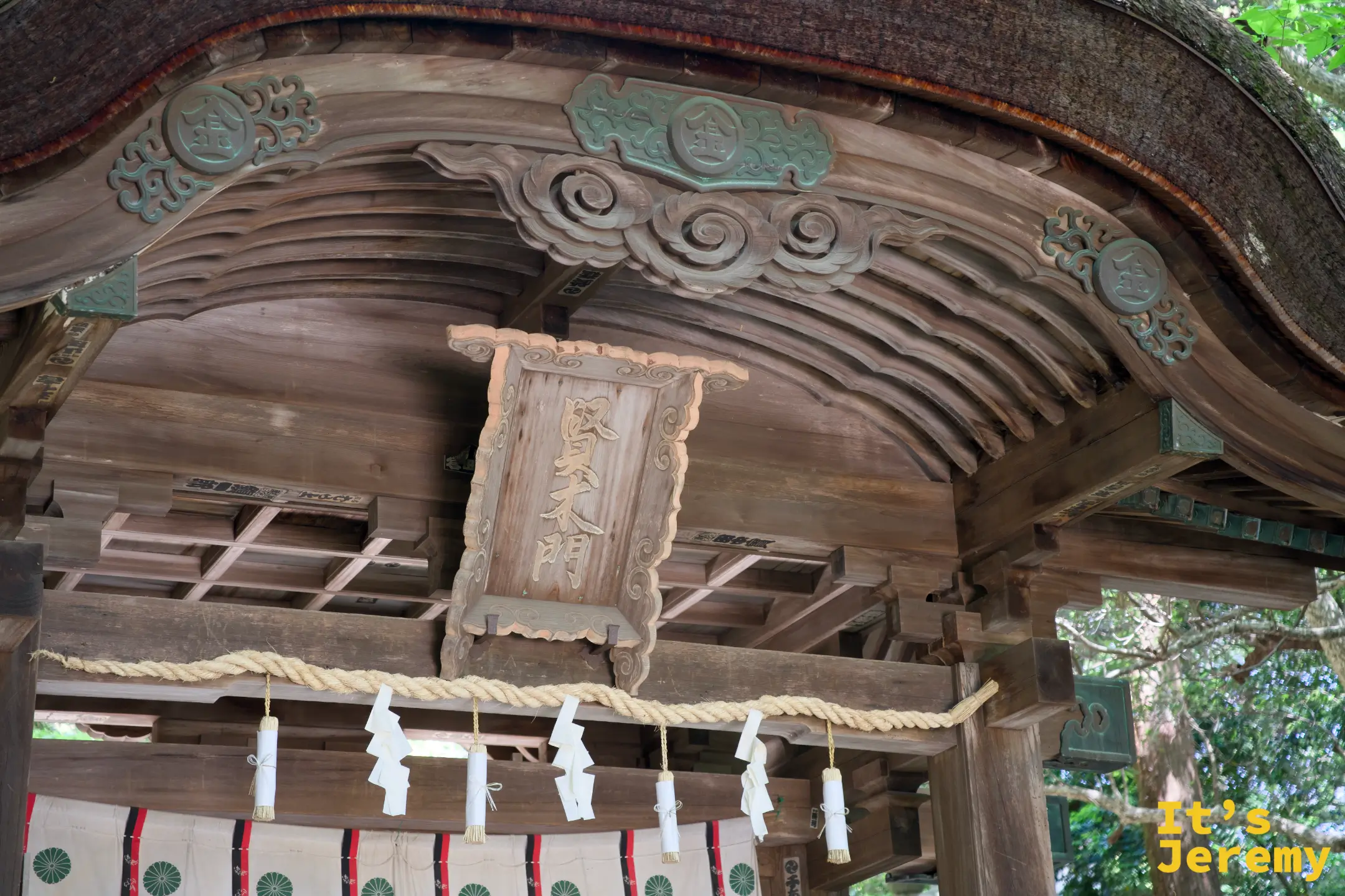 賢木門屋頂內側特寫，木雕雲紋裝飾精緻，中央掛著「賢木門」木匾，下方懸垂注連繩與紙垂