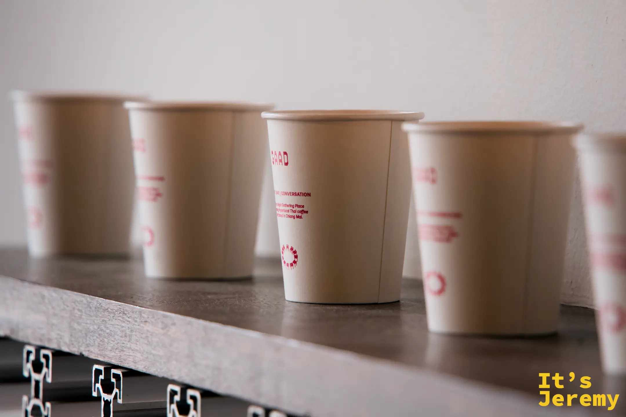 GAAD 紙杯特寫，杯身印著 GAAD、BAR / CONVERSATION 字樣，周圍虛化