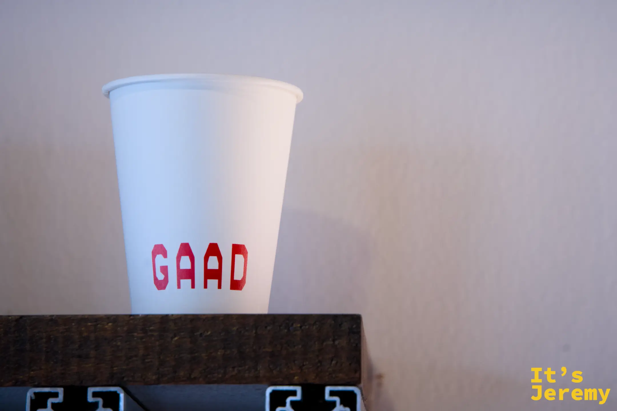 單只 GAAD 紙杯在暖光中，紅色 GAAD 字樣清晰