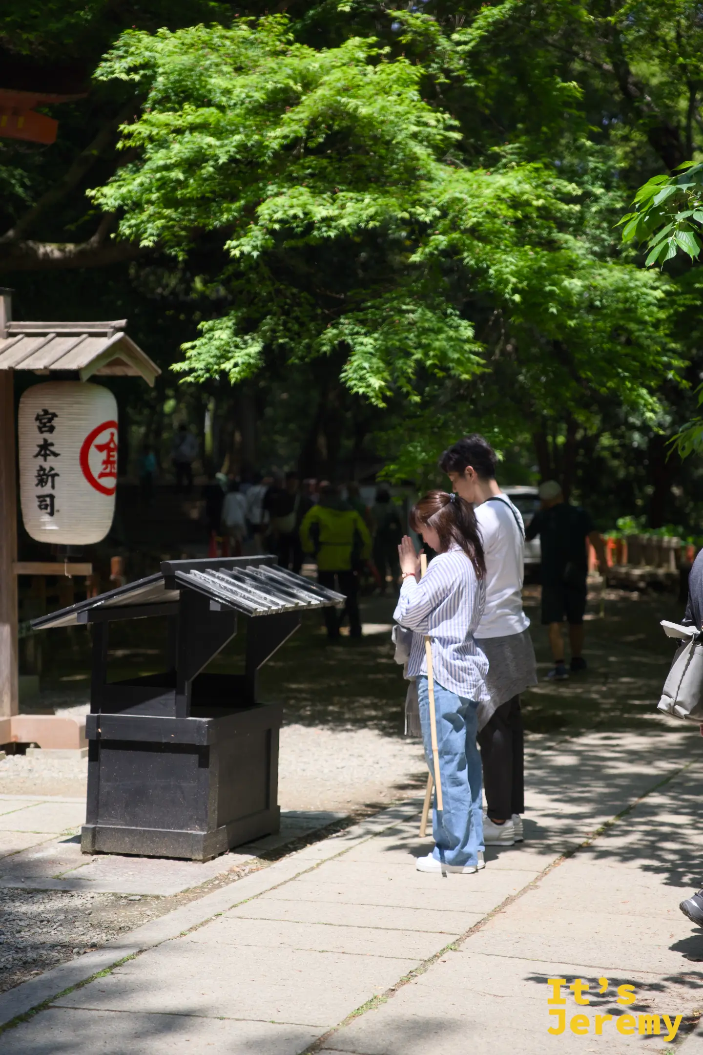一對情侶在白峰神社前的奉納台雙手合十虔誠祈願，旁邊懸掛著「宮本新司」字樣的燈籠