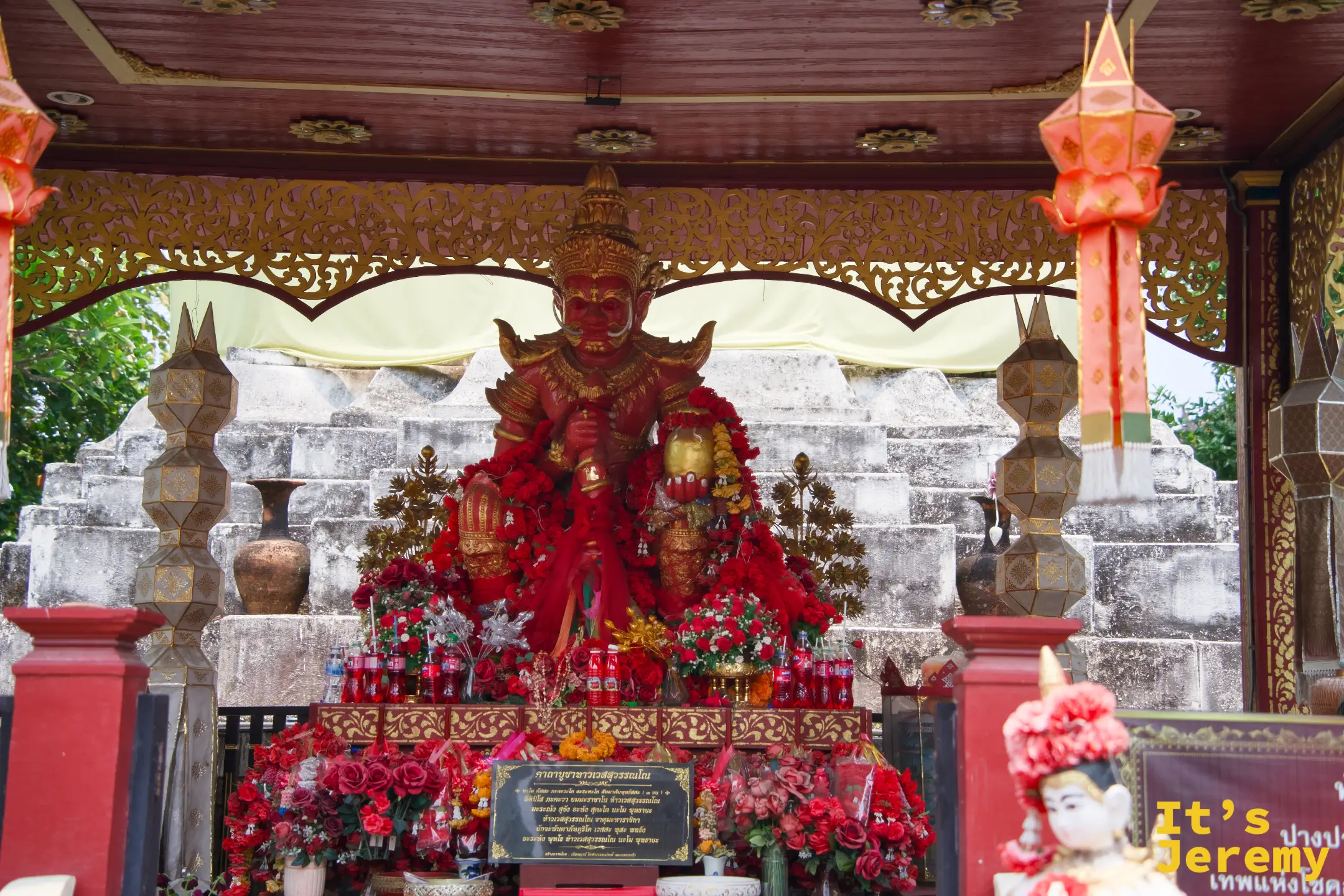 財神亭全景——亭內供奉紅衣夜叉神像，左右兩側各立金色柱燈，神像前的供桌擺滿紅色供品