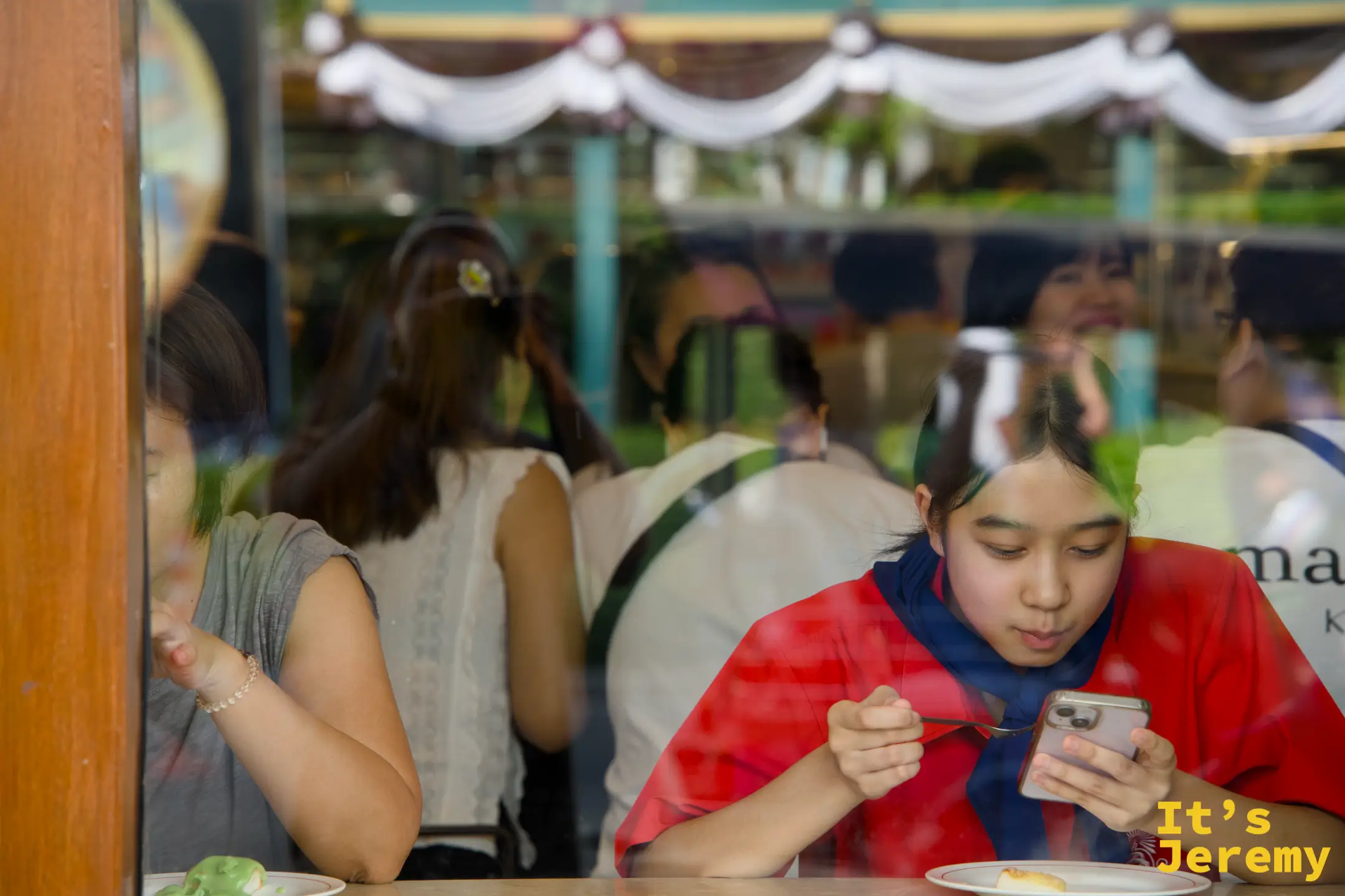 窗邊座位，一位食客正在邊吃烤吐司邊滑手機，窗外是帝梭路的街景