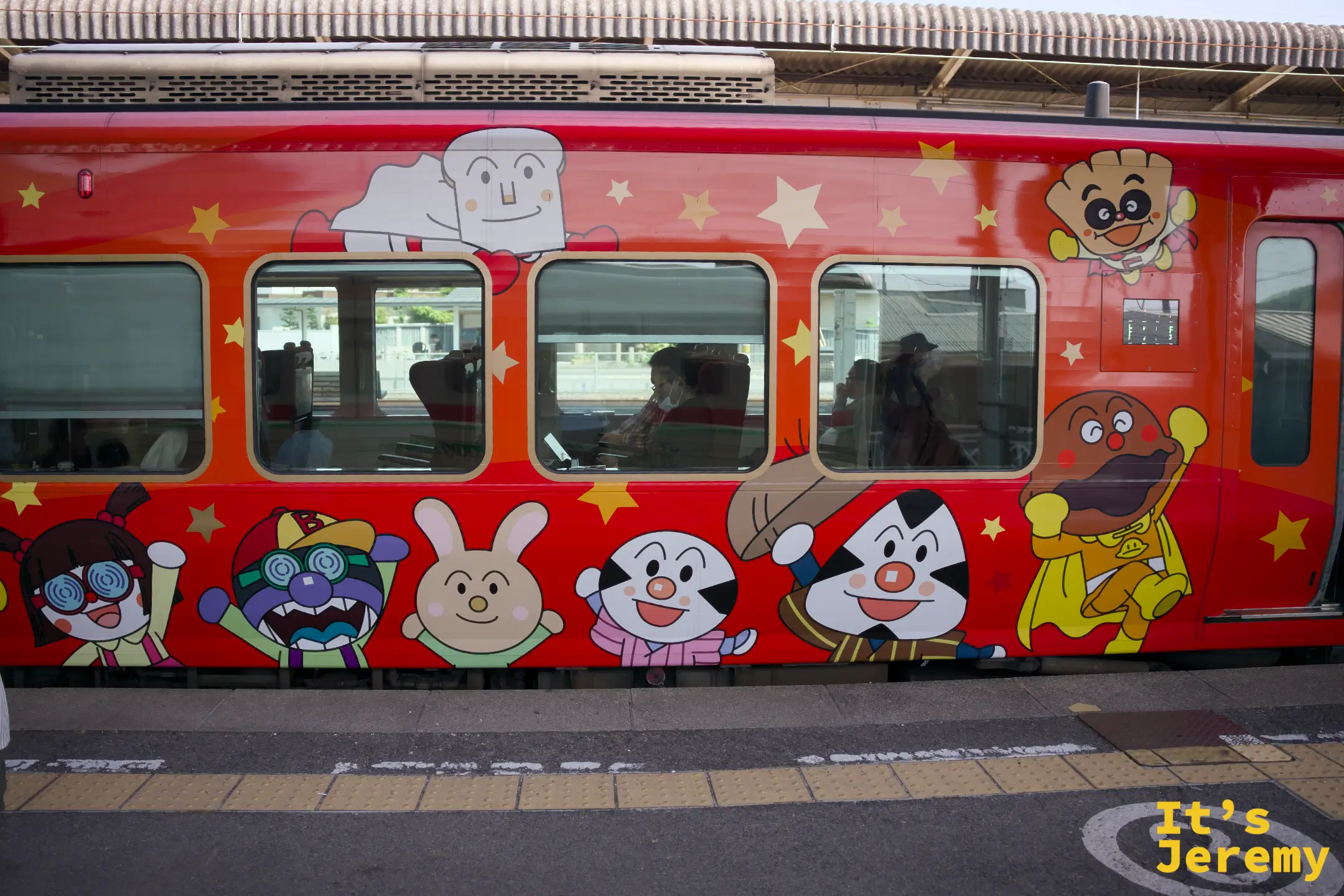 麵包超人列車側面，橘紅色車廂上排列著全系列麵包超人角色，圖案密集且色彩鮮豔