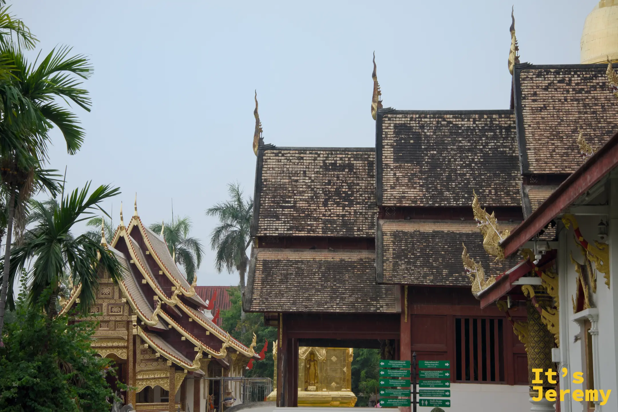 寺廟院內全景，多座殿宇並排，綠色指示路牌清楚可見