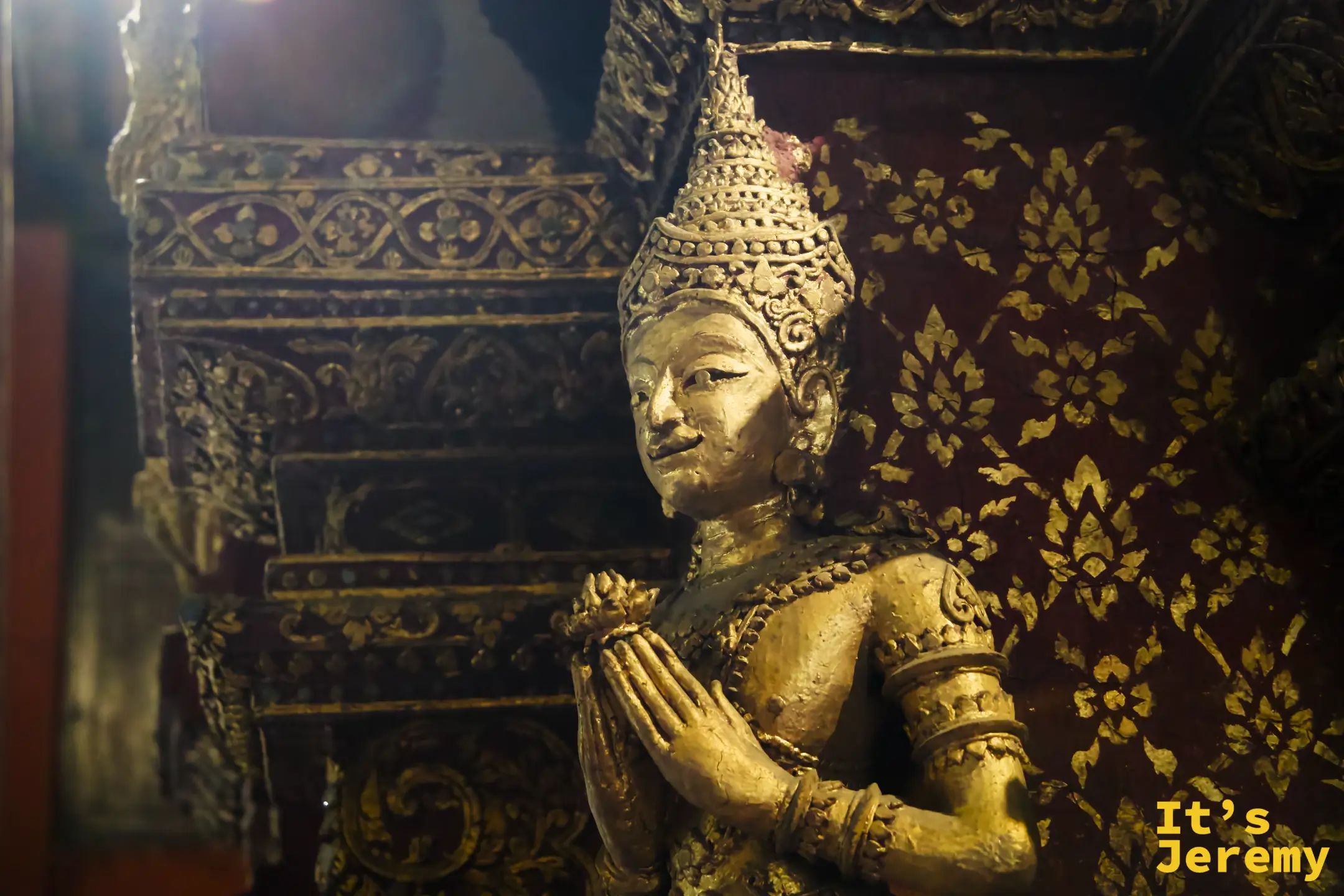 殿內天使合十像（Theppanom），以蘭納金底壁畫為背景，低頭虔誠合掌