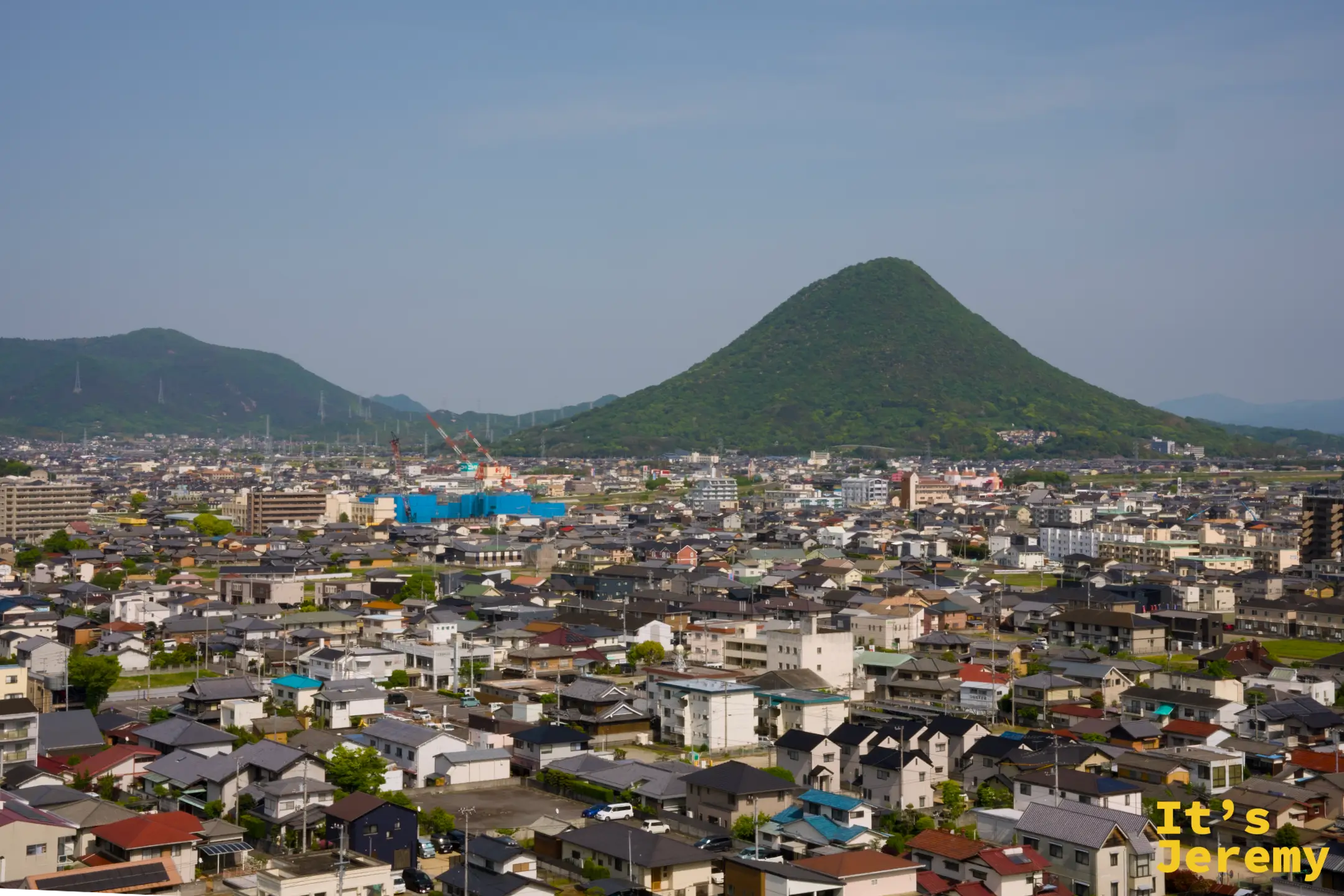 城上俯瞰，遠方一座圓錐形的飯野山（讚岐富士）獨自突起於平野之上