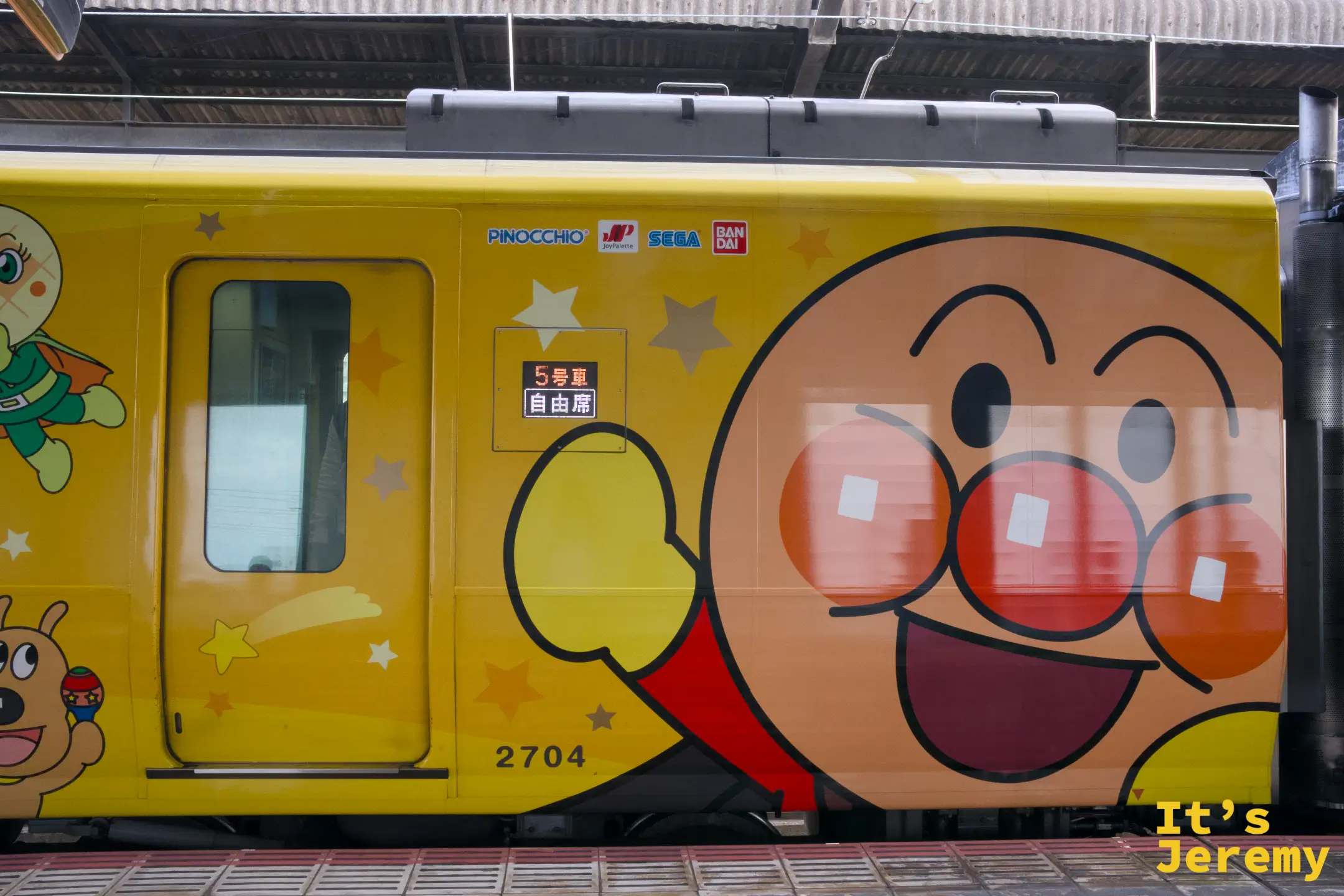 黃色麵包超人列車（2704）側面特寫，整片車廂壁是巨大的麵包超人臉，「5 號車 自由席」標示清楚