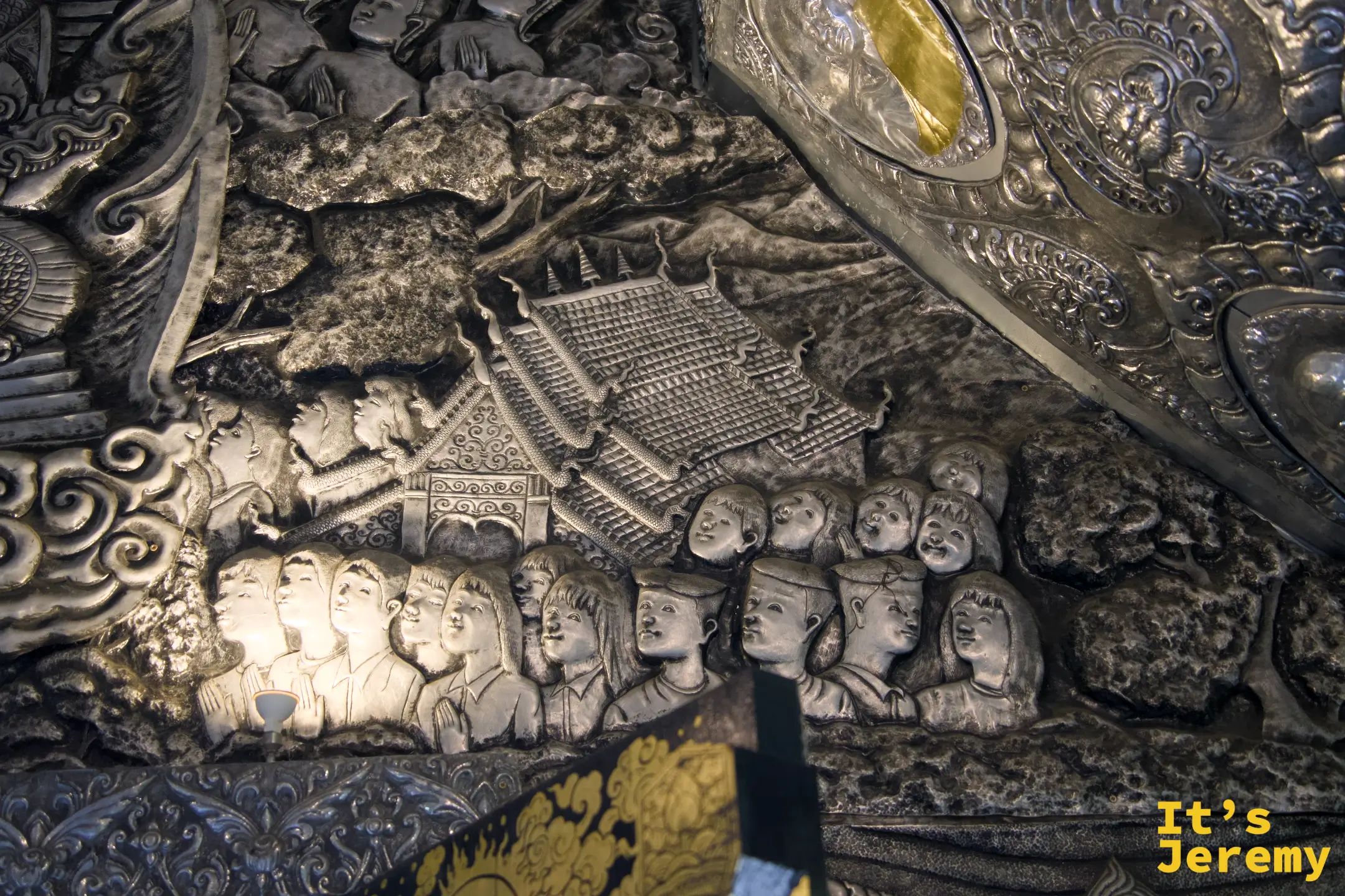 天花板浮雕，人物群像在寺廟前聚集，人物比例與構圖展現出高超的技藝
