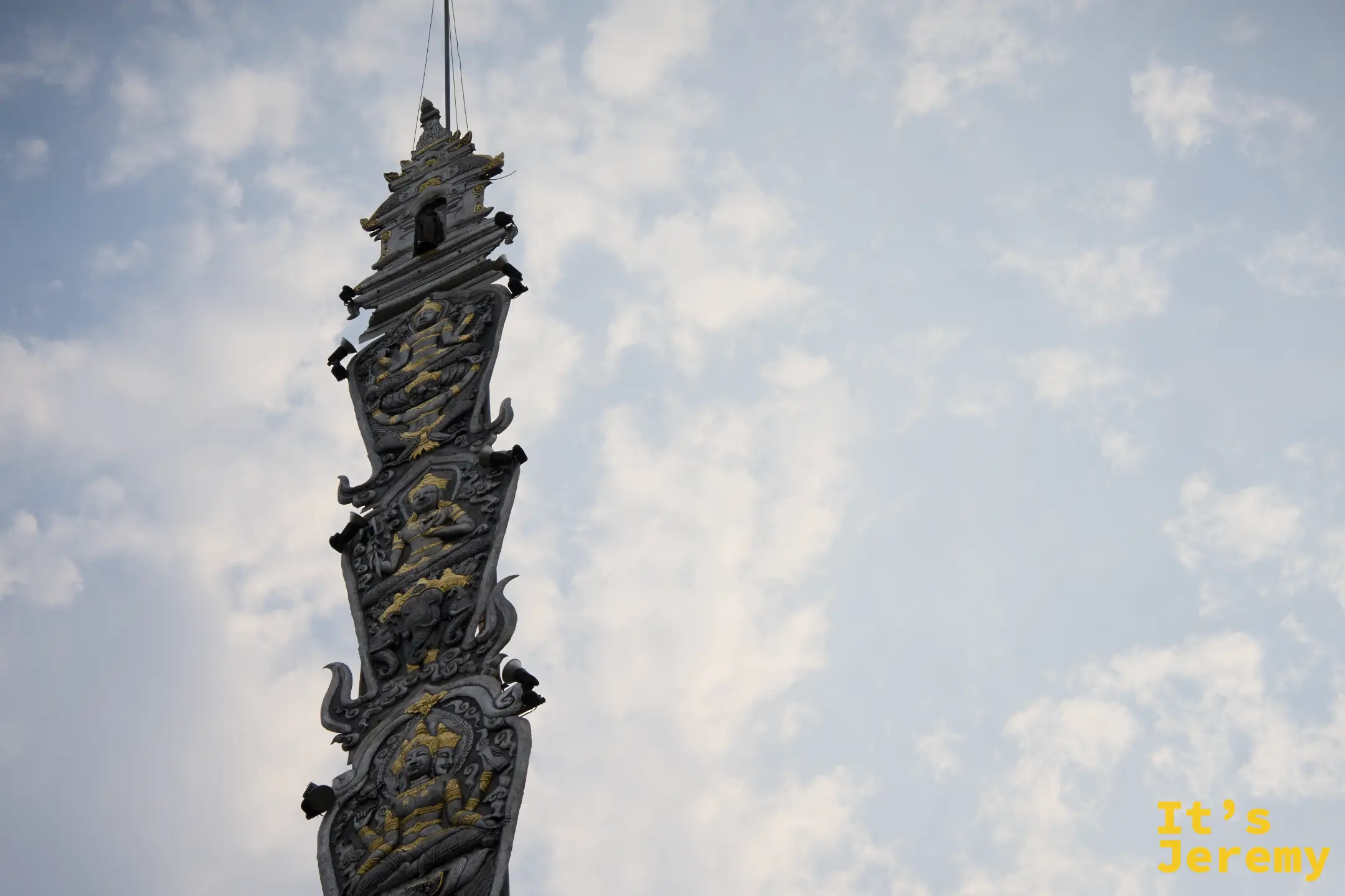 旗幡柱仰拍，金色神明層層排列而上，幾乎消失在天空中