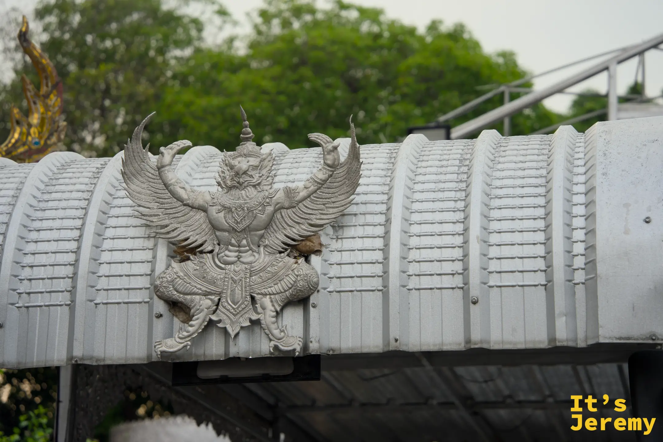寺廟圍牆上的大鵬金翅鳥（Garuda）浮雕，翅膀全開，銀白色材質更顯威嚴