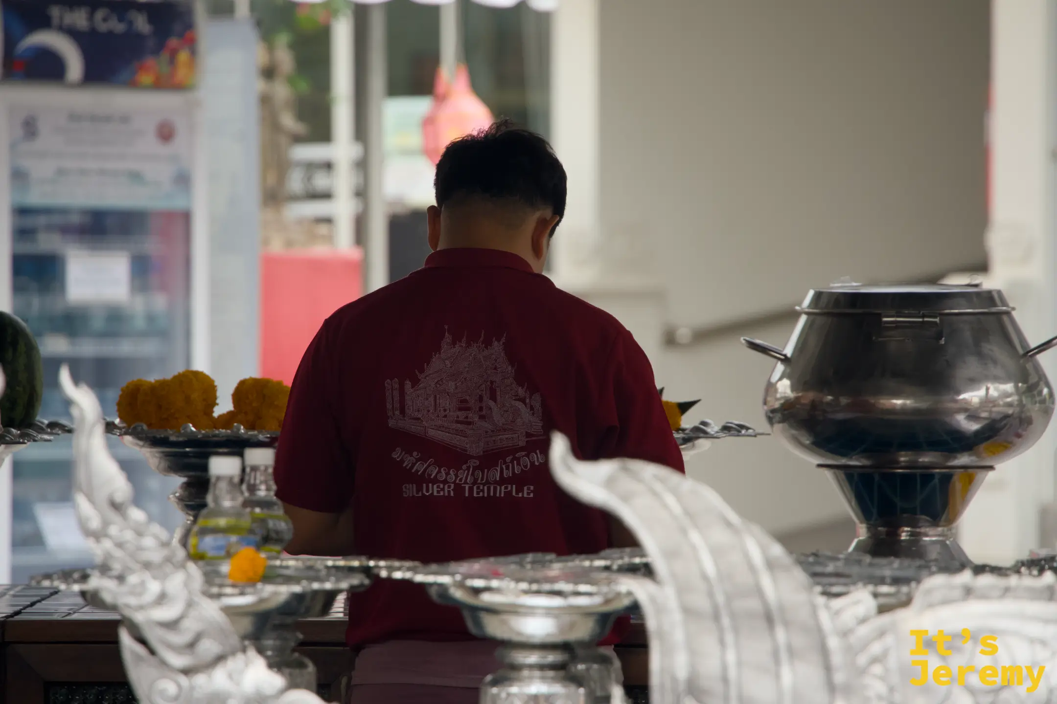 穿著印有銀殿圖案紅色制服的工作人員，正在整理供台，供品整齊擺放