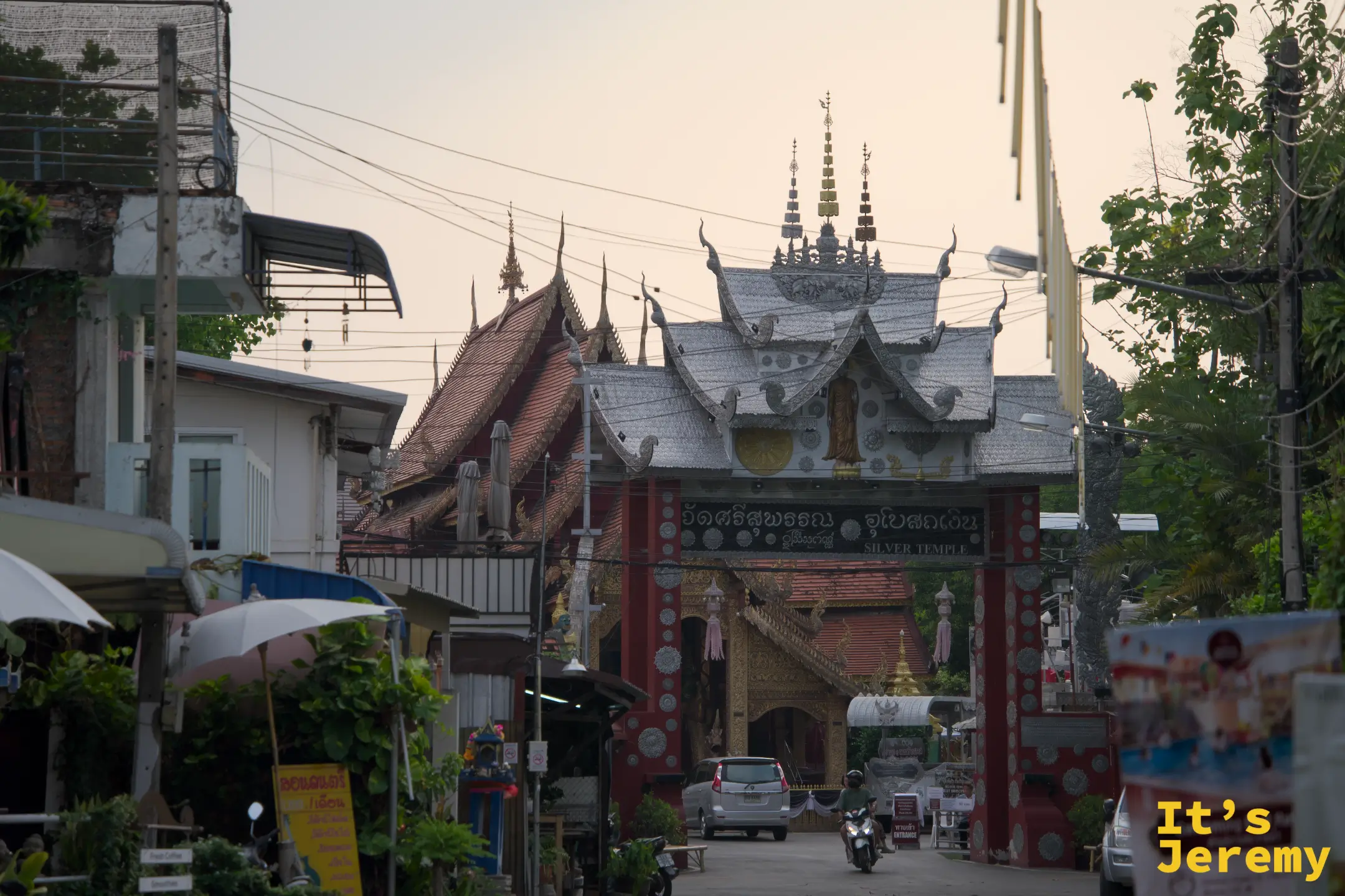 傍晚從 วัวลาย 路望向銀殿大門，入口招牌就嵌在街道正中央